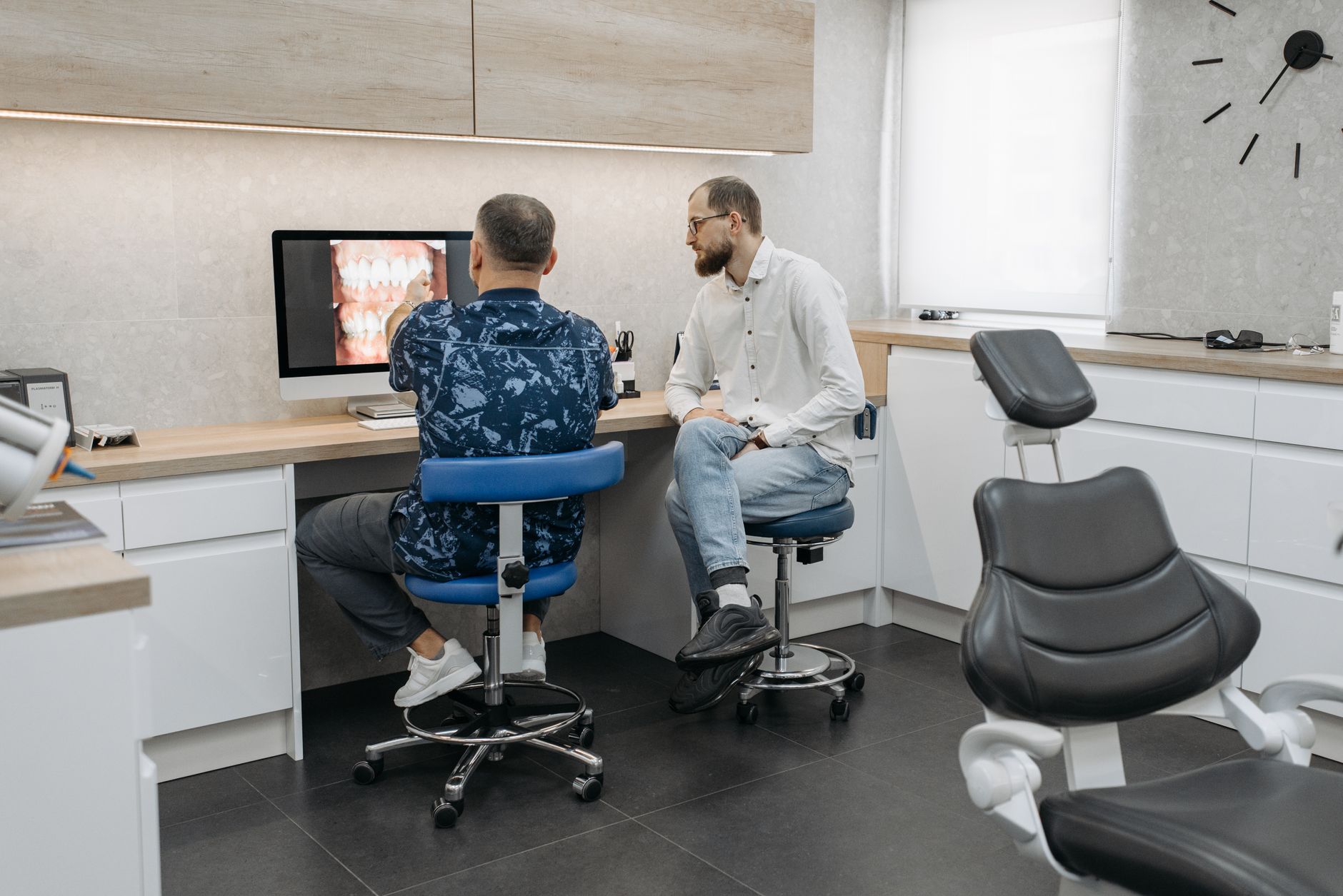 Two dental professionals analyze a patient's dental x-ray at a modern clinic, utilizing advanced technology.
