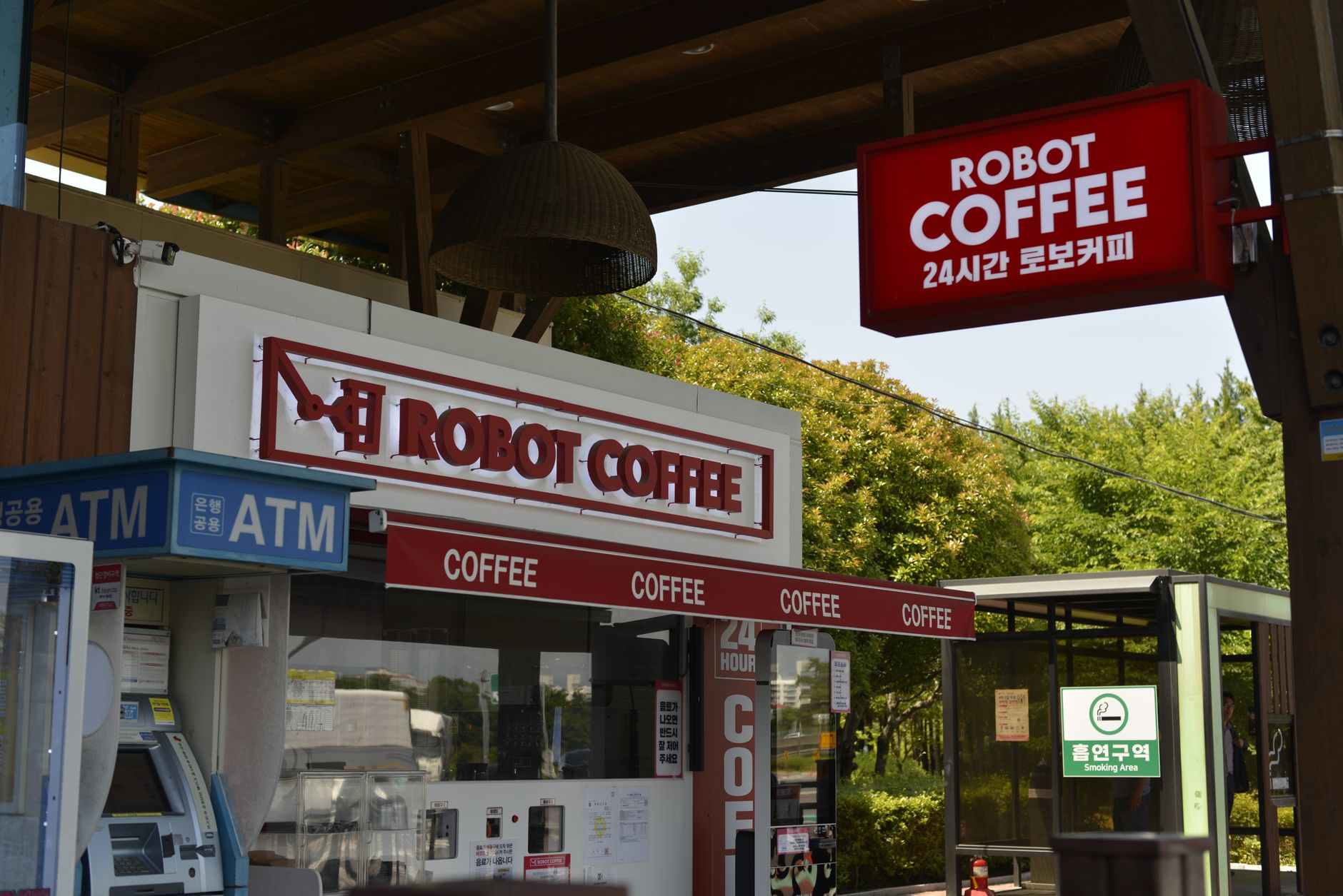 Robot Coffee shop exterior with ATM and visible signage in a lush outdoor setting.