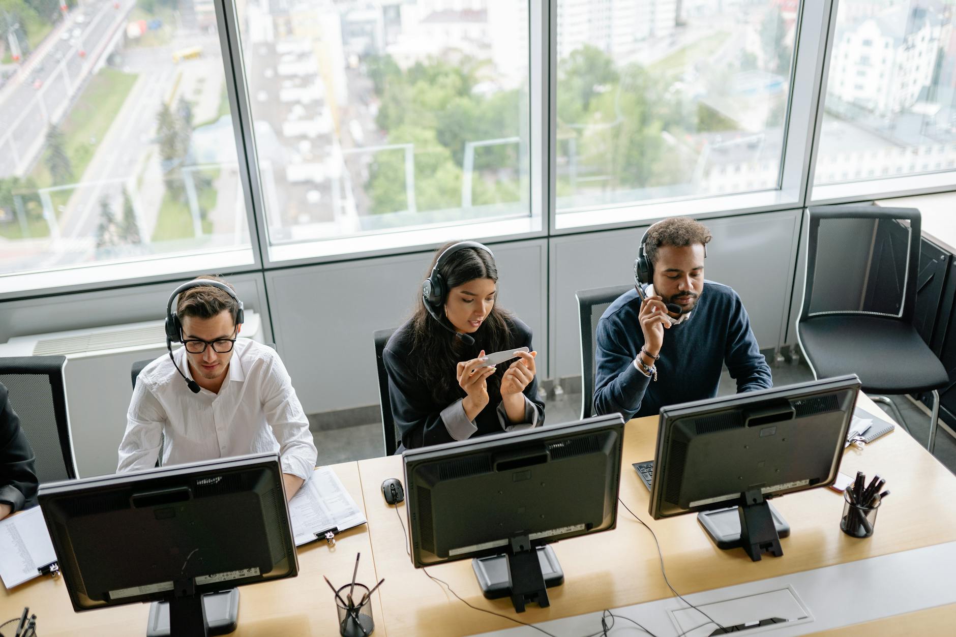 Diverse call center team working in a bright office space with a city view.