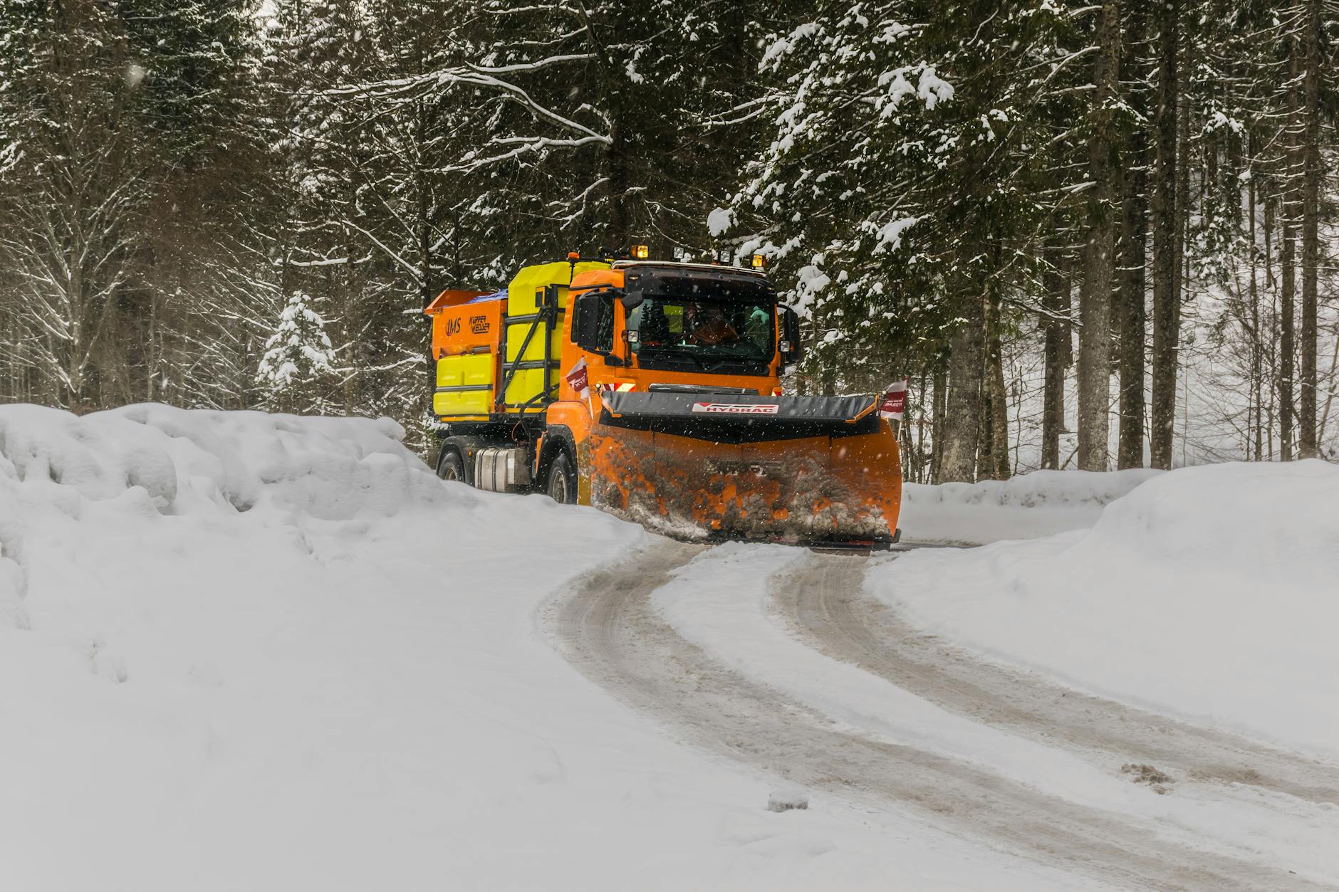 Snow plow clearing large parking lot at night
