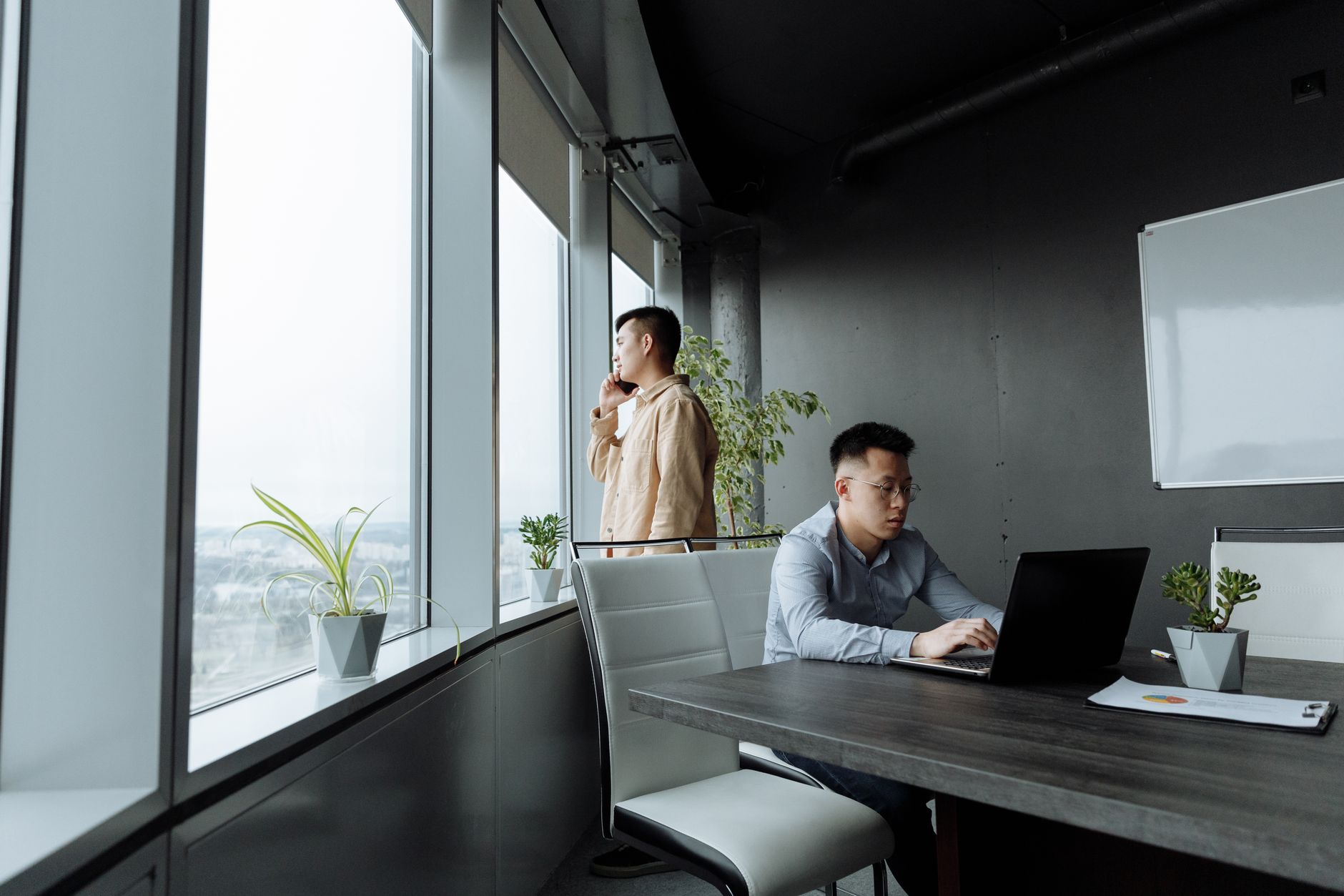 Two Asian men collaborating in a modern office space, focusing on teamwork.
