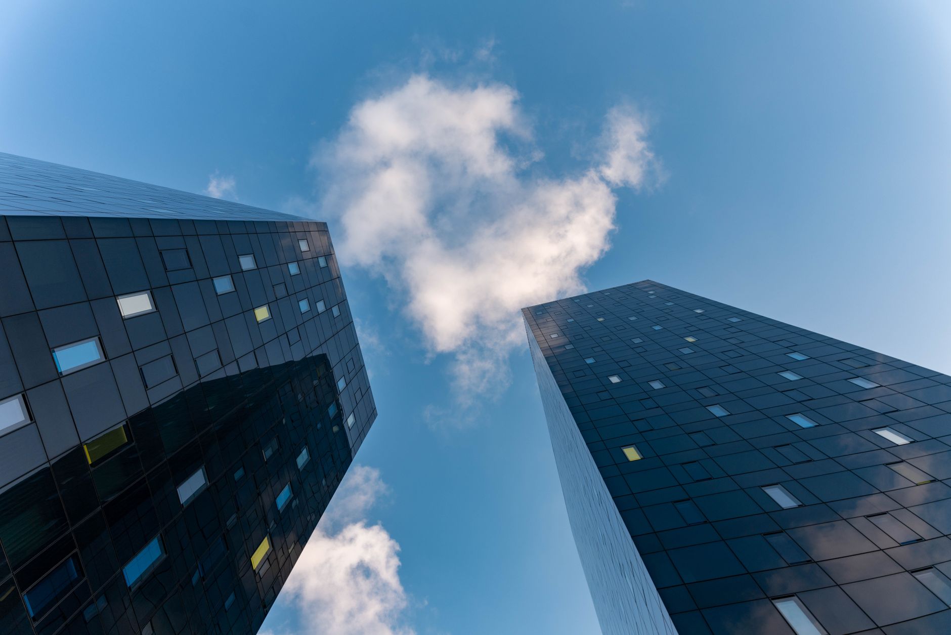Low-angle photo of glass skyscrapers against a cloudy sky, showcasing modern architecture.