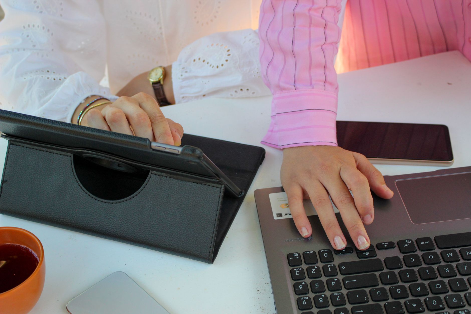 Office scene showing teamwork using a laptop, tablet, and smartphone.