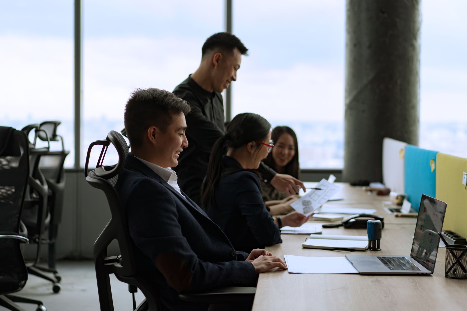 Group of coworkers in a modern office having a collaborative discussion. Professional and lively setting.