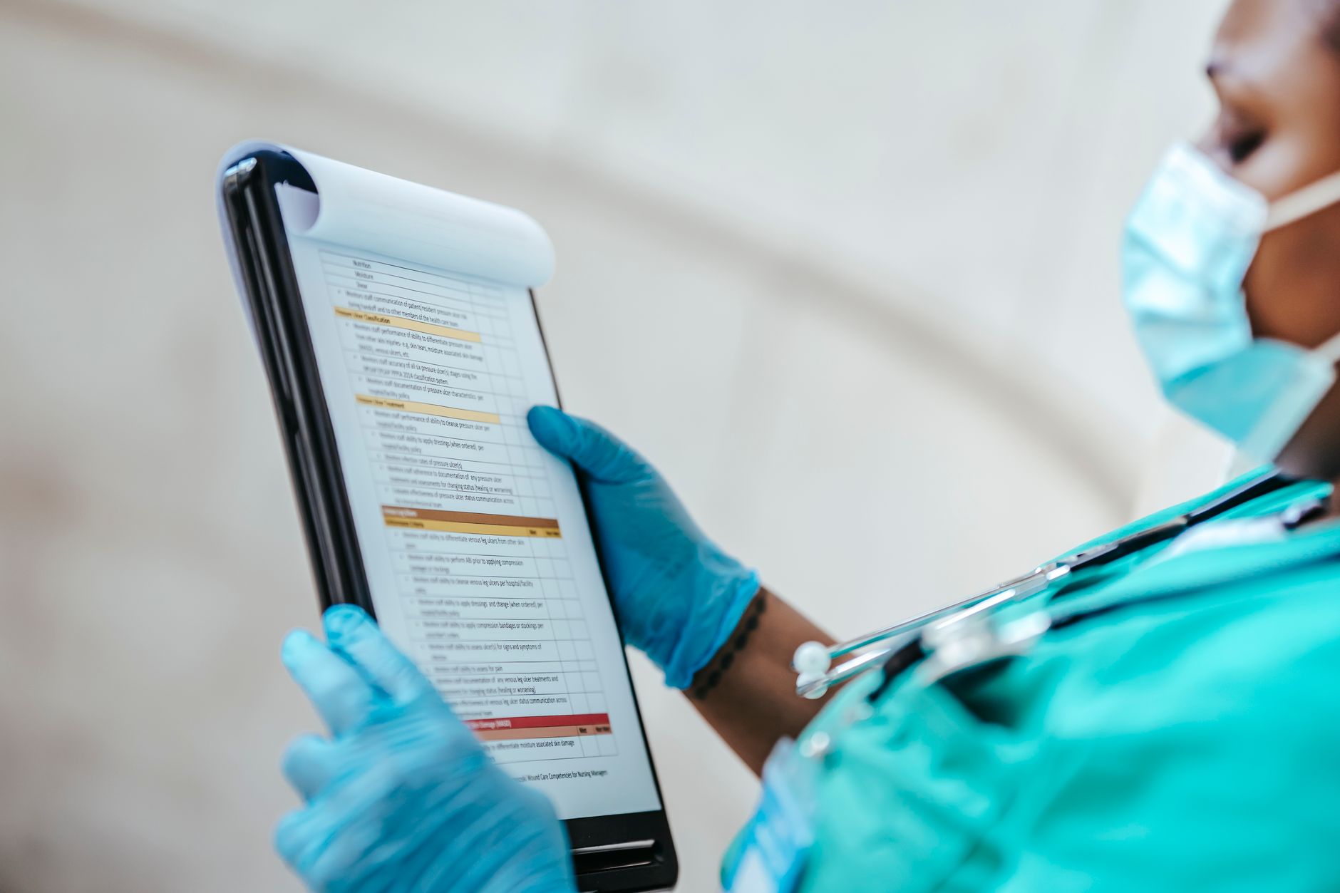 Side view of crop African American female medic in uniform reading text on paper at work