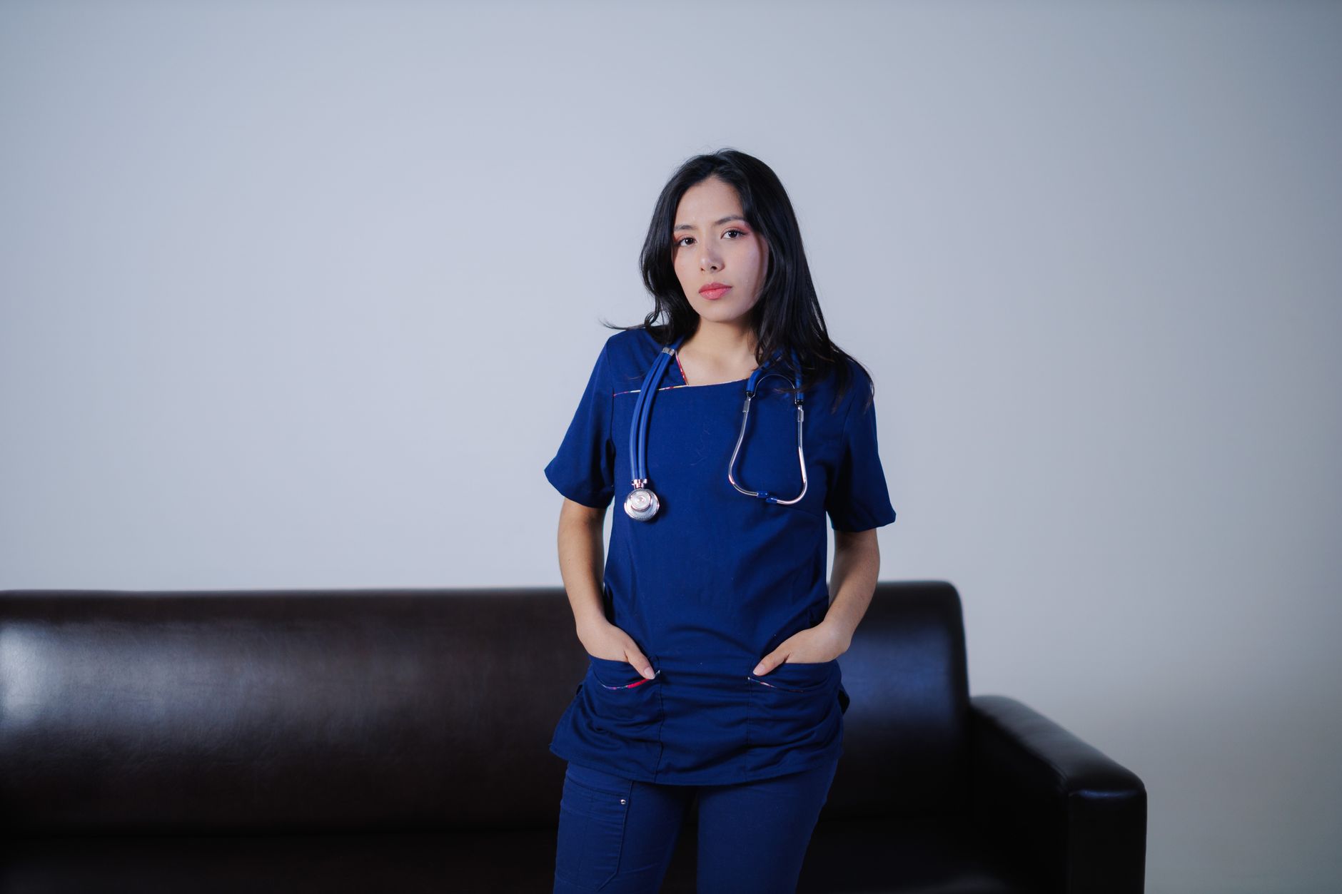 Young female nurse standing confidently indoors with stethoscope, showcasing professionalism and care.