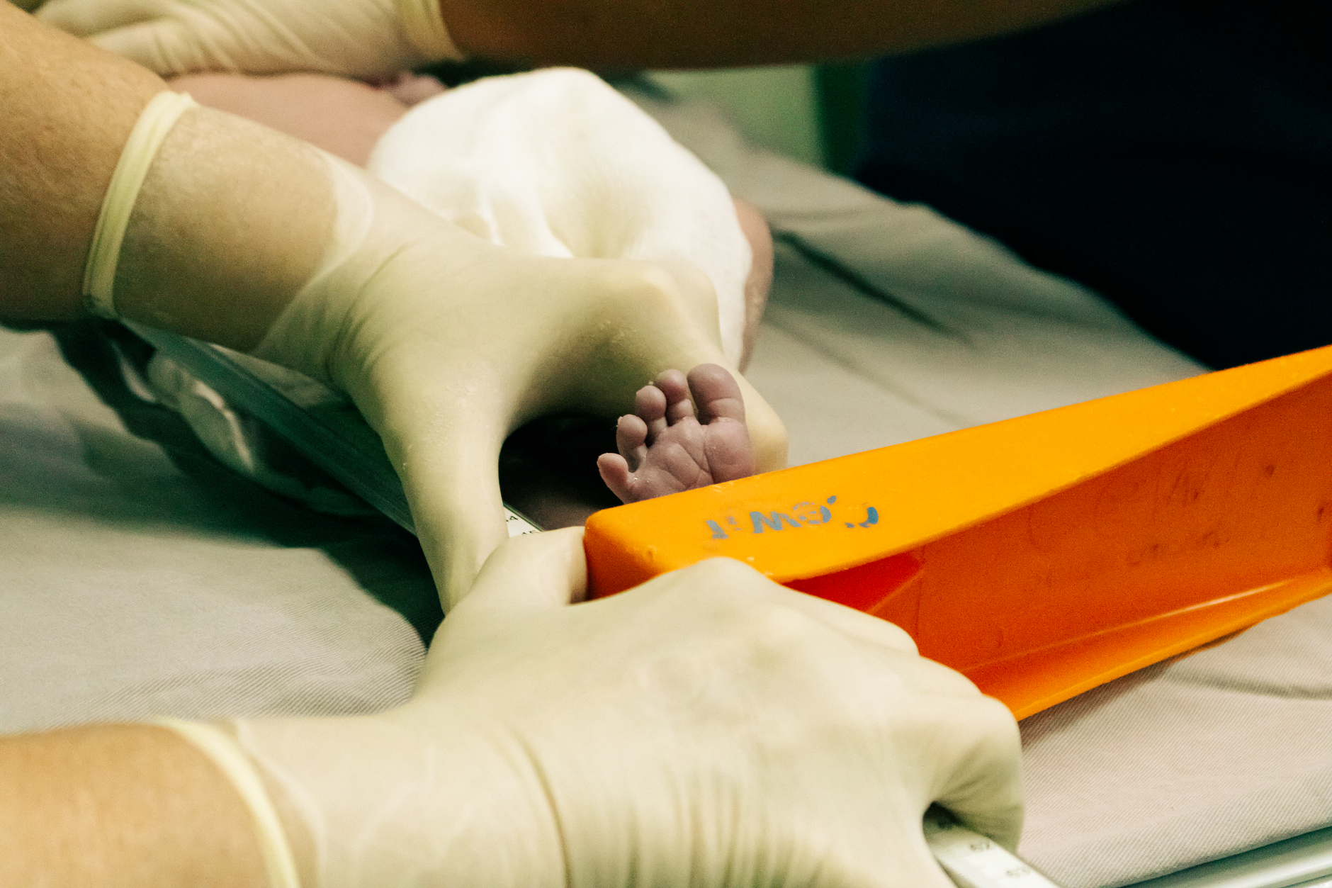 Newborn's foot being measured by a nurse in medical setting with care.