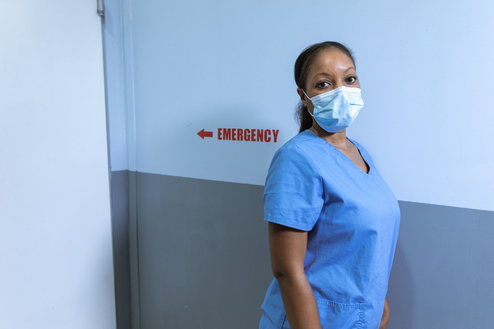 Nurse wearing mask in hospital emergency corridor for safety.