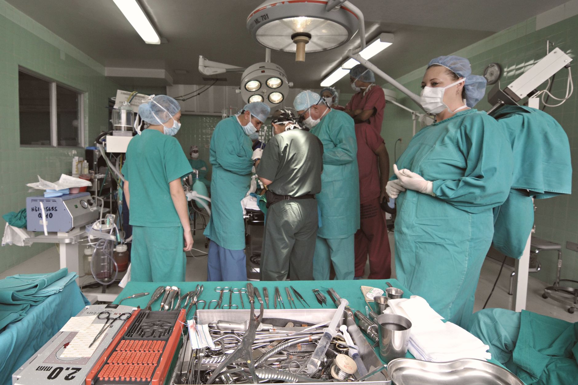 Medical team conducting surgery in a sterile operating room with surgical tools on display.