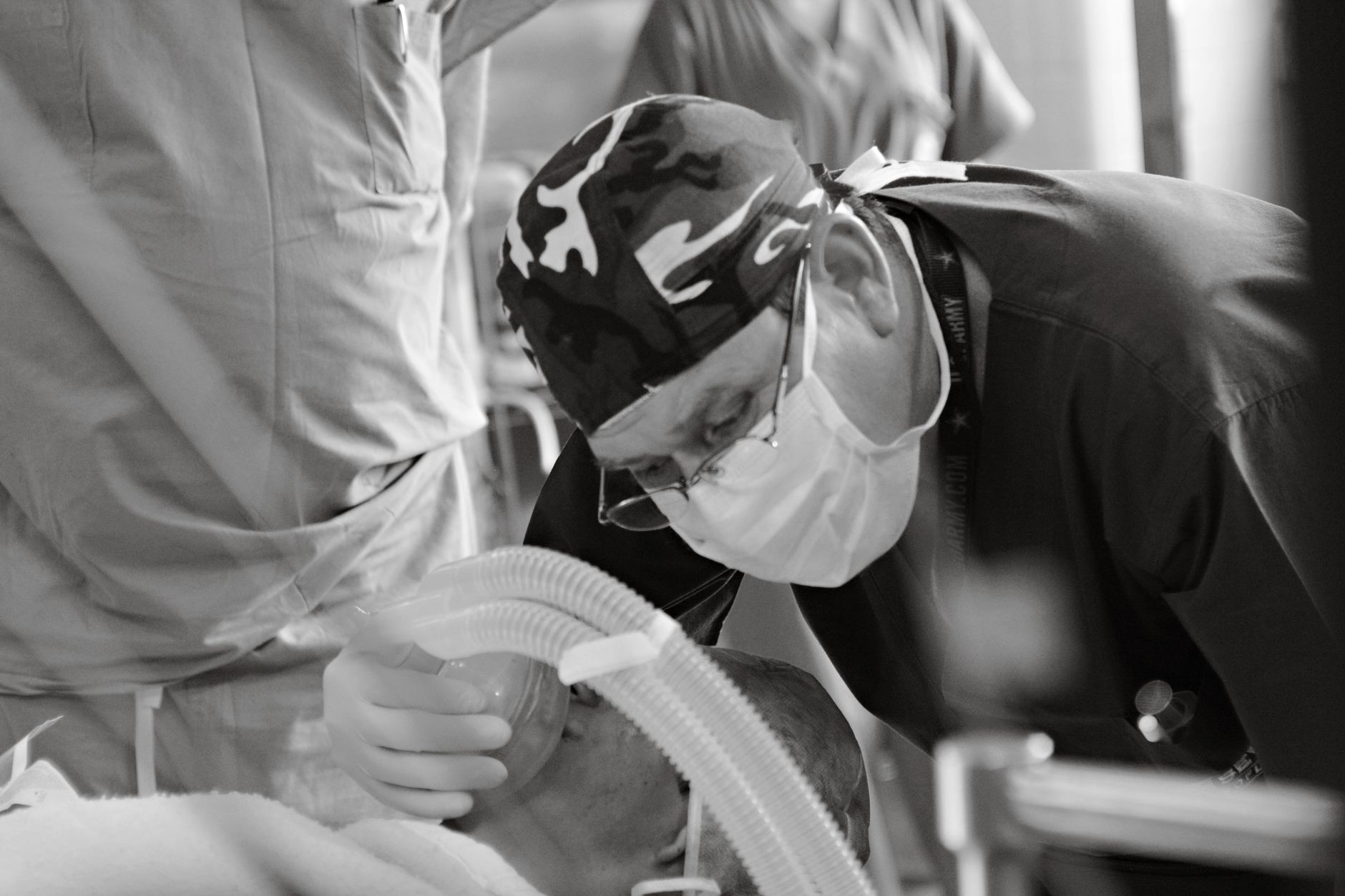 Black and white image of a focused surgeon in the operating room, providing life-saving medical care.