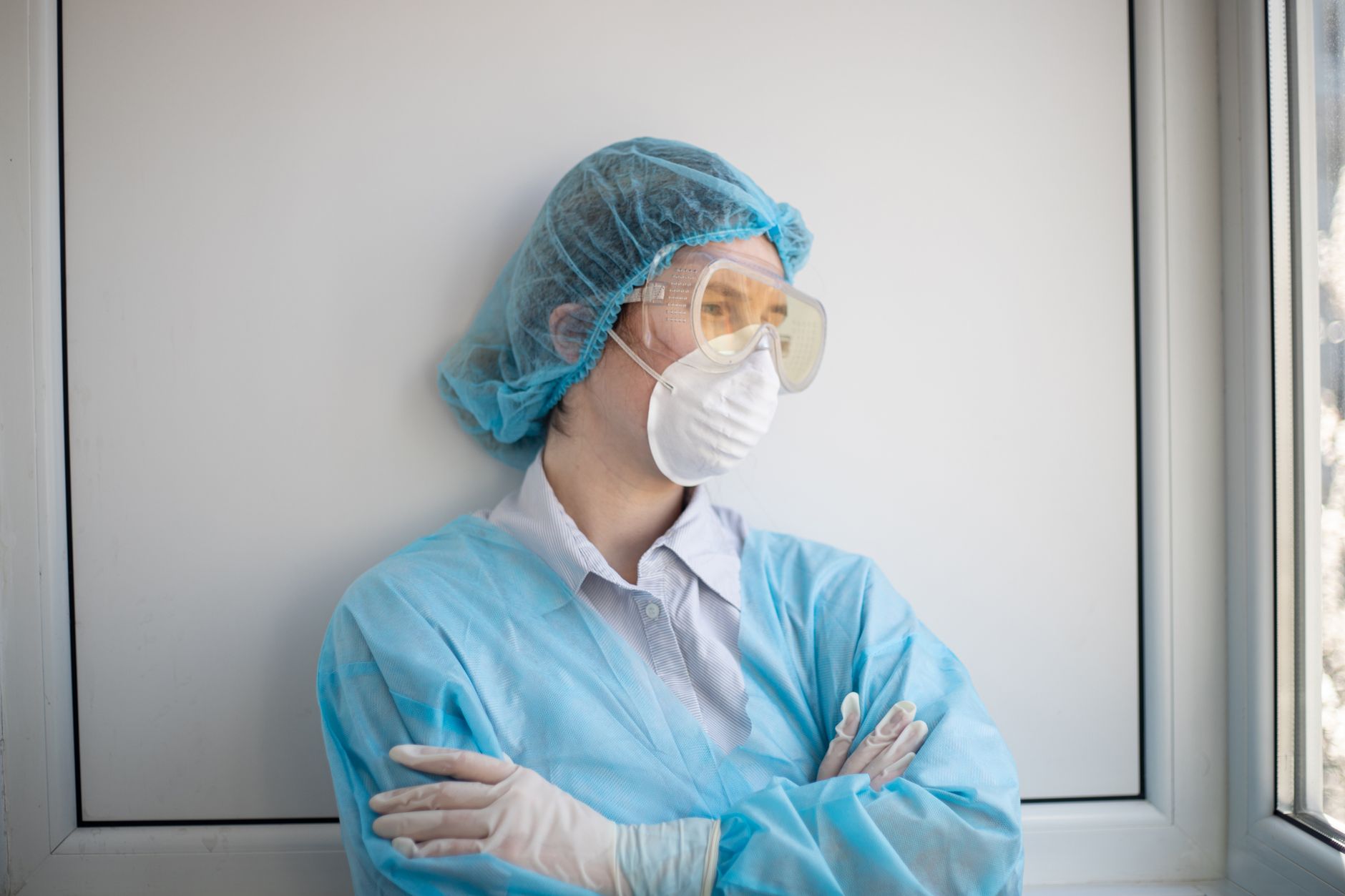 Female healthcare worker in protective gear stands indoors, symbolizing resilience in healthcare.
