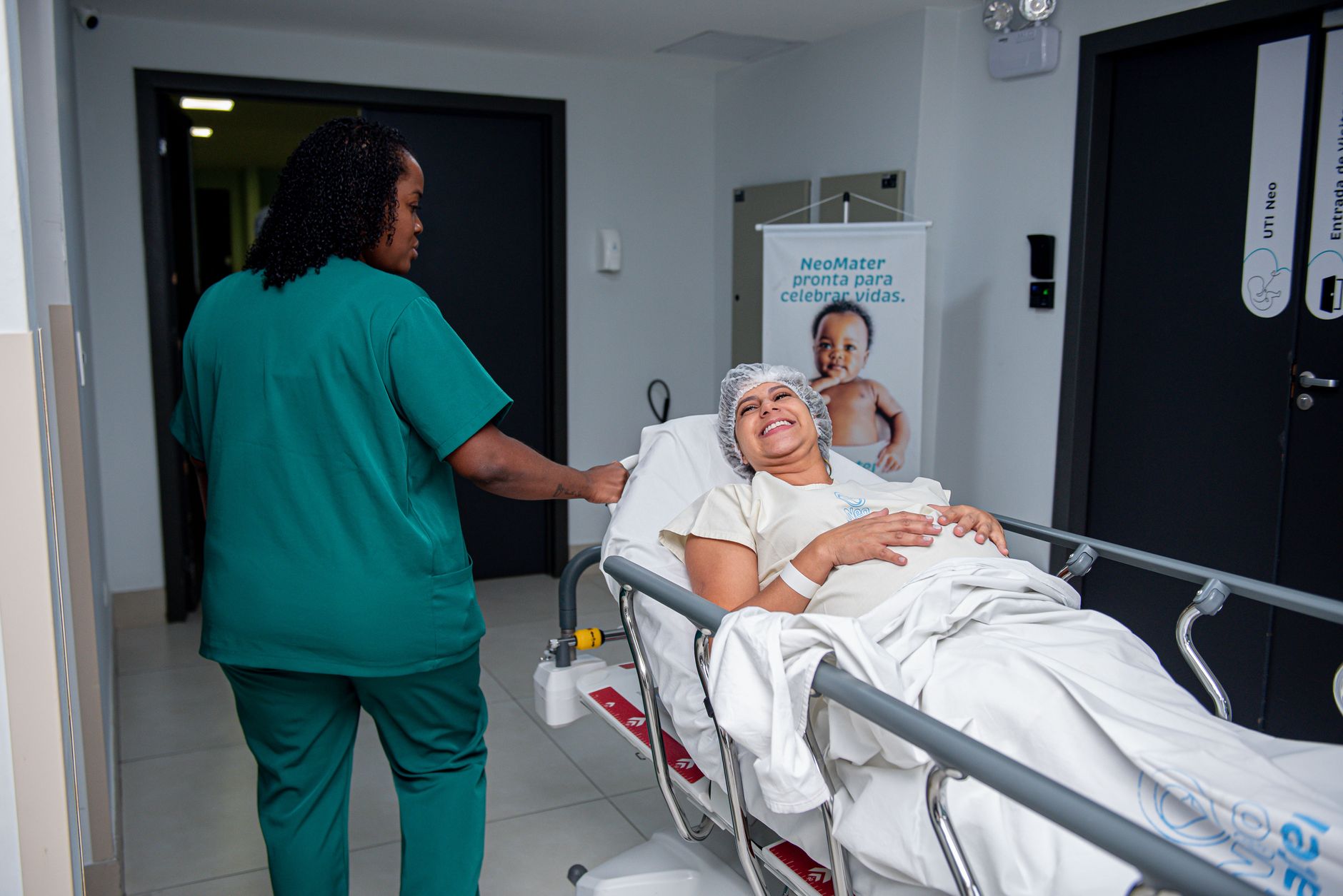 A caring nurse assists a patient in a hospital corridor with a joyful demeanor.