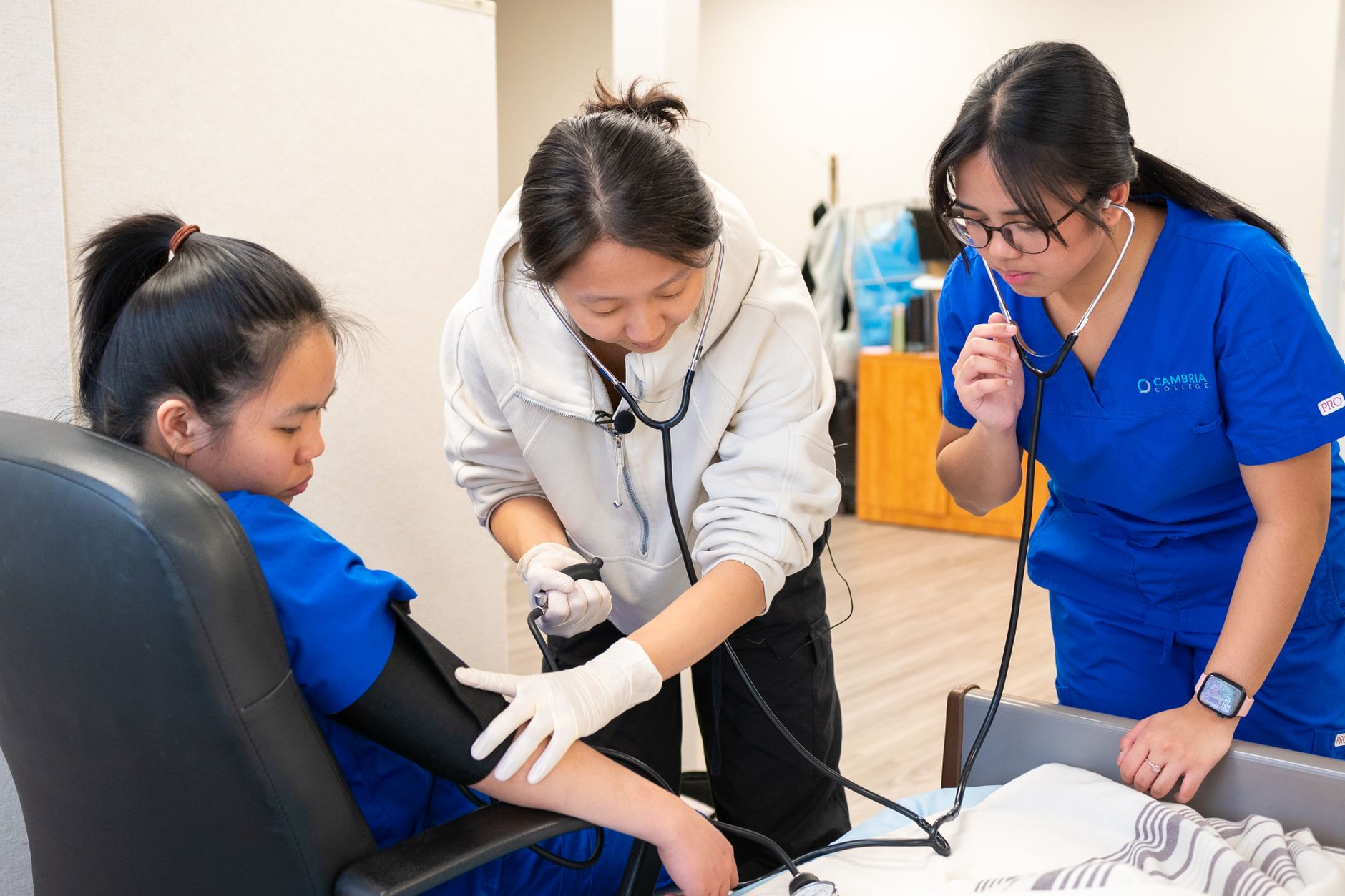 Nursing students engaged in practical training for blood pressure measurement in a clinical setting.