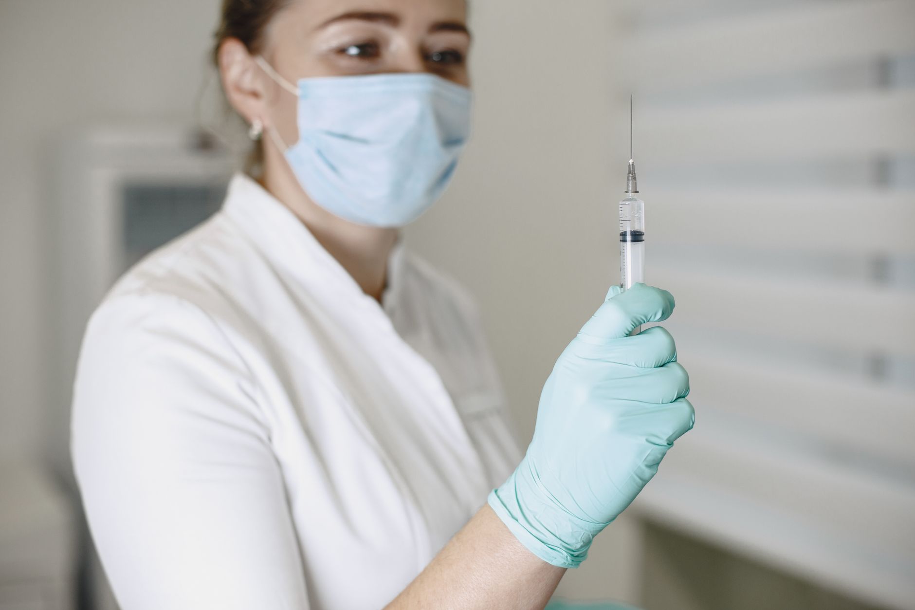 Healthcare worker prepares syringe for vaccination, showcasing safety precautions.