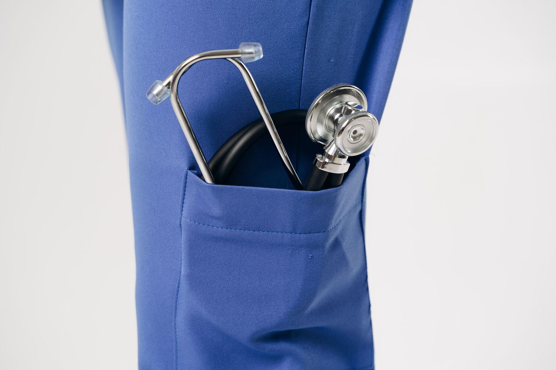 Closeup of a stethoscope in a blue pocket, representing healthcare professionalism.