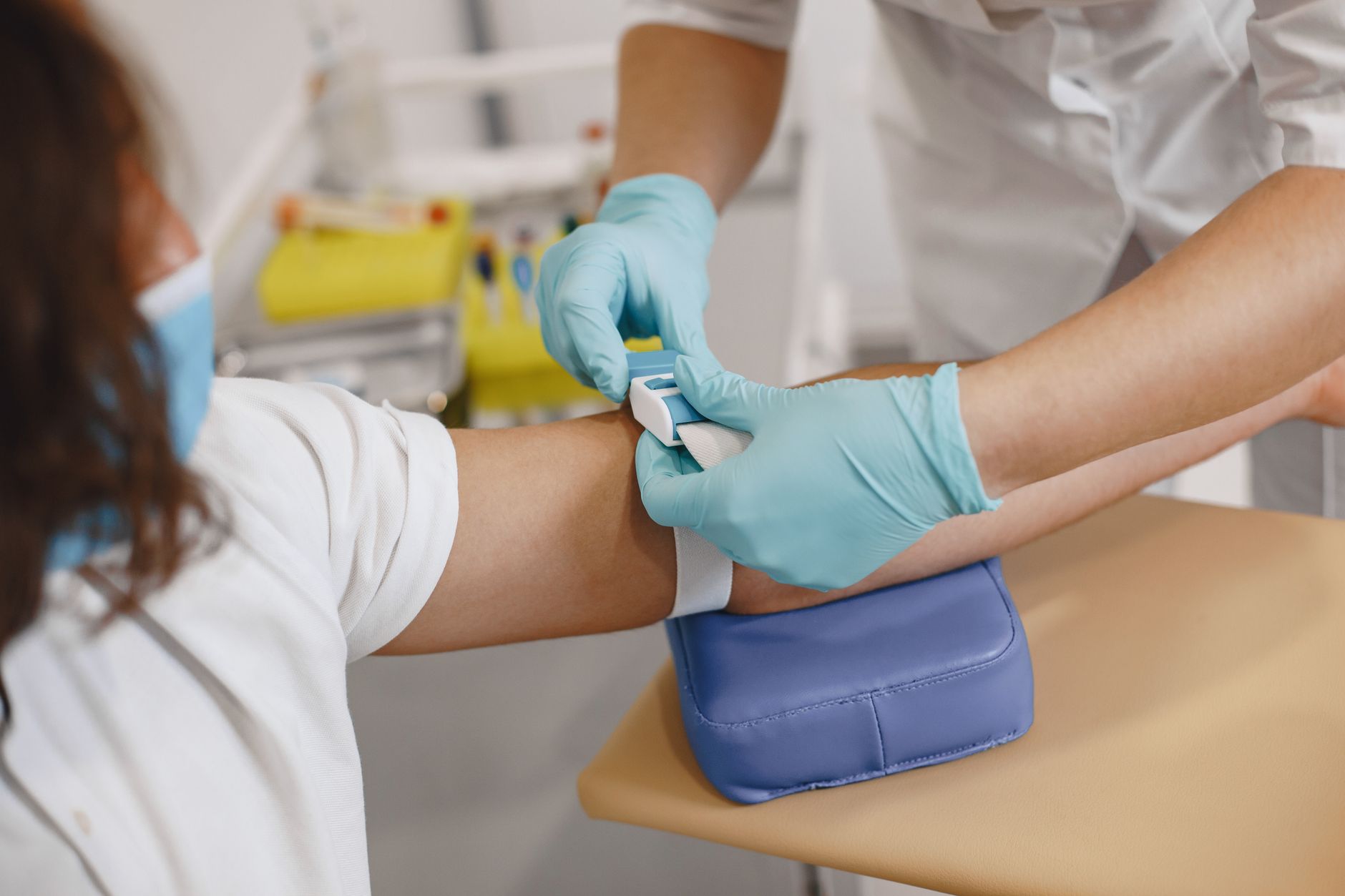 Close-up of a healthcare worker preparing a patient's arm for a blood draw in a clinic setting.