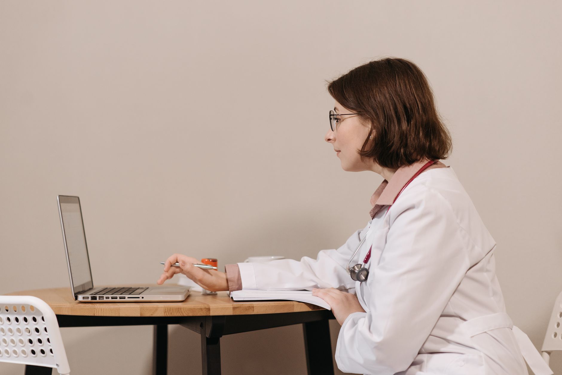 Enfermeira estudando para o NCLEX em um laptop, com livros ao lado