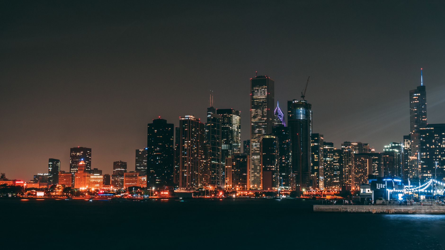 Dramatic nighttime view of Chicago's iconic skyline with illuminated skyscrapers along the waterfront.