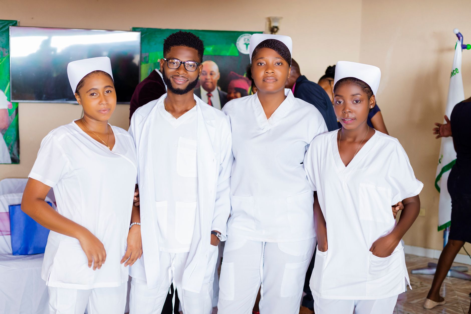 Four healthcare professionals wearing white uniforms, posing indoors.