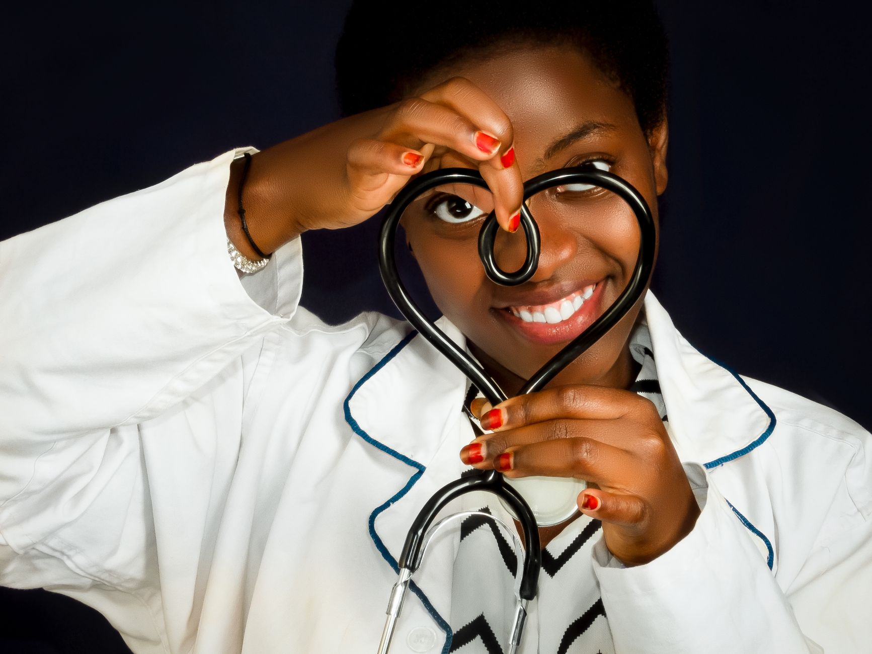 Smiling female doctor with a stethoscope shaped as a heart signifying care and compassion.