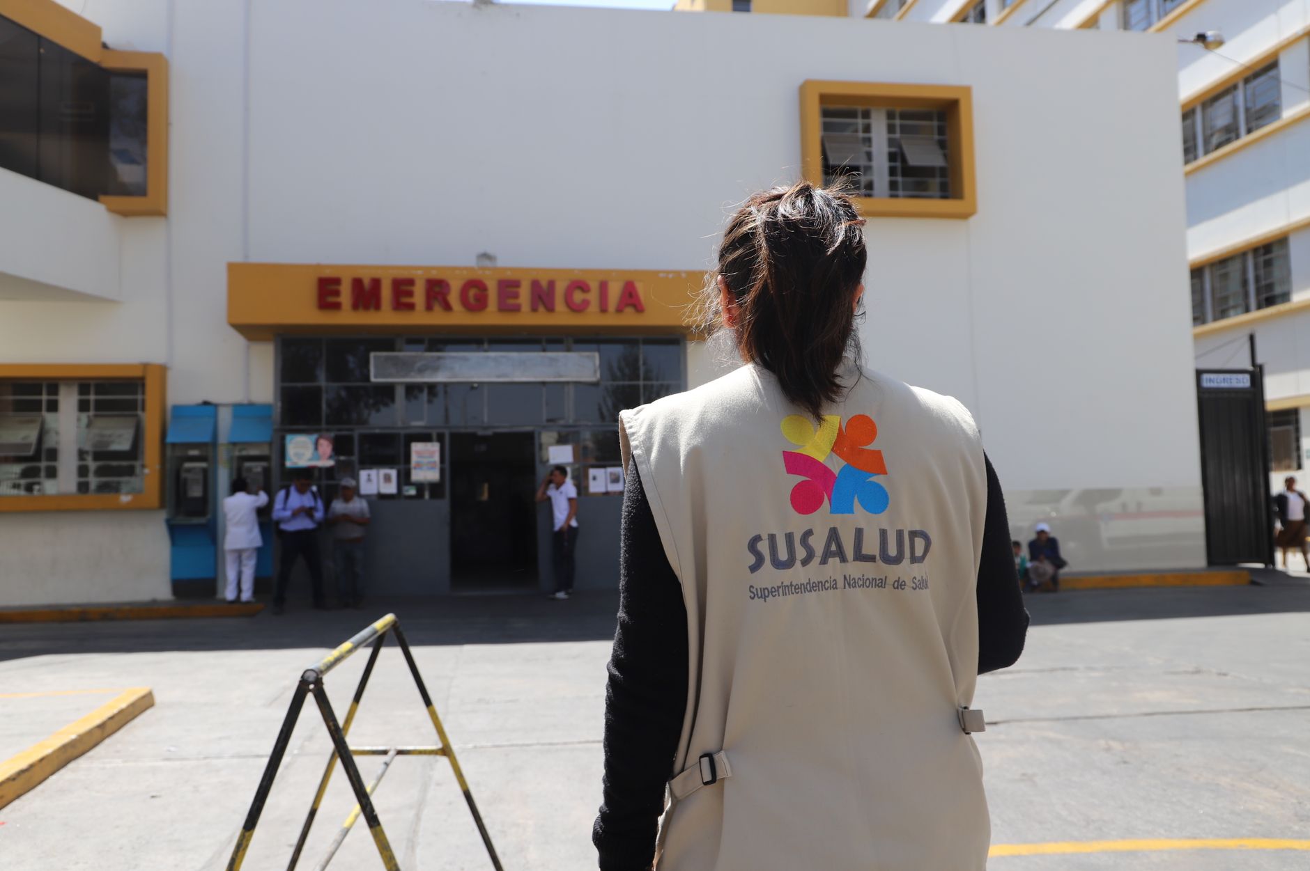 A SUSALUD official outside an emergency entrance at a hospital during the day.