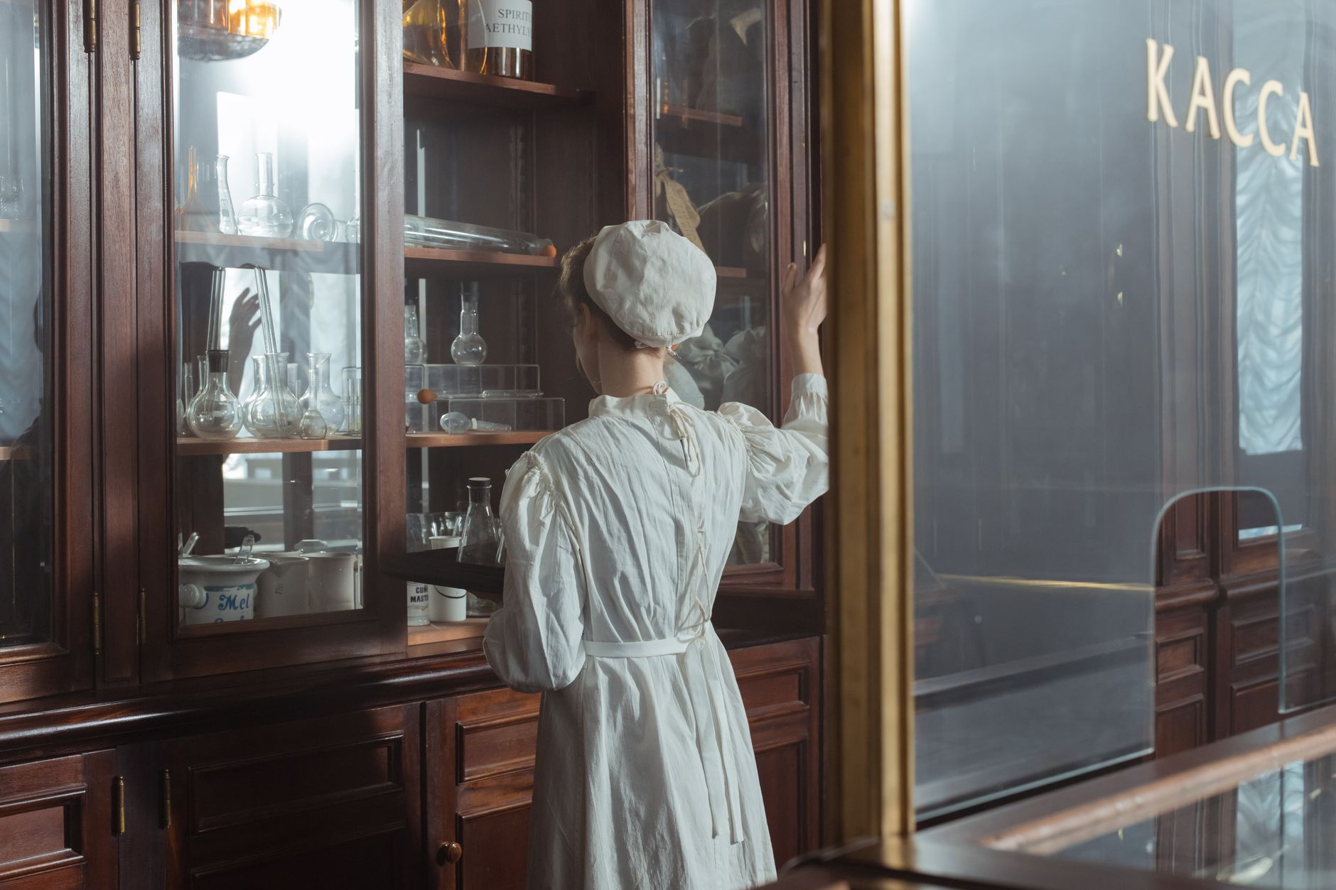 A vintage scene with a chemist in historical attire examining laboratory equipment.