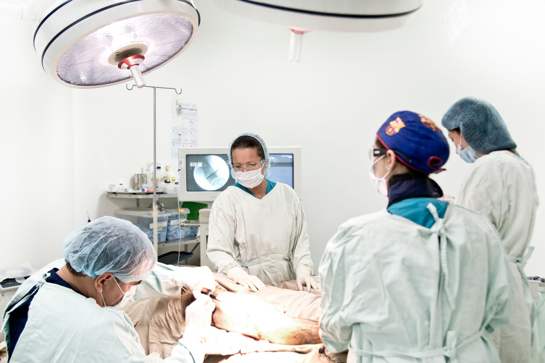 Surgeons and medical staff conducting a surgical operation under bright lighting in a hospital setting.