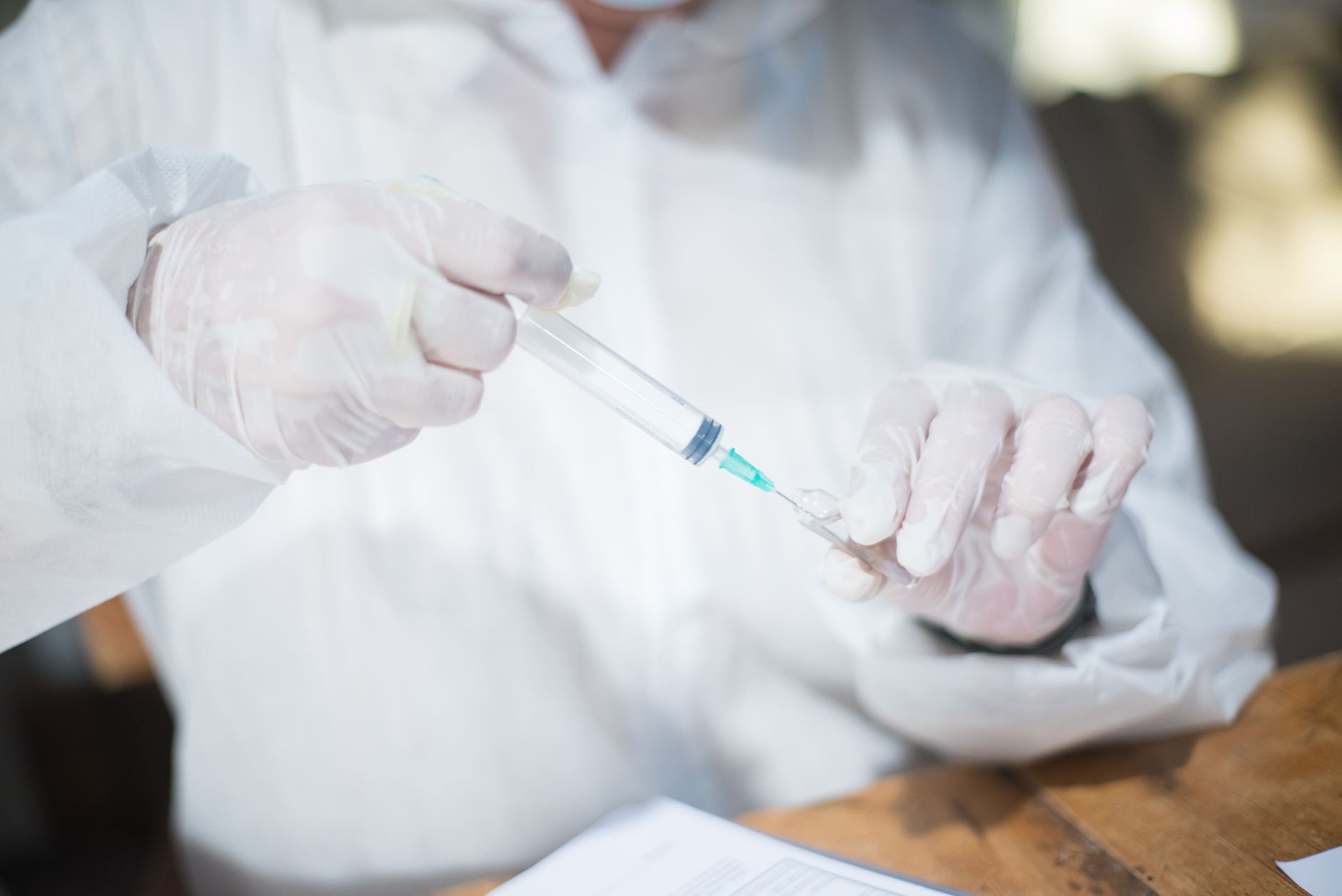 Healthcare worker in protective gear holding a syringe, close-up.