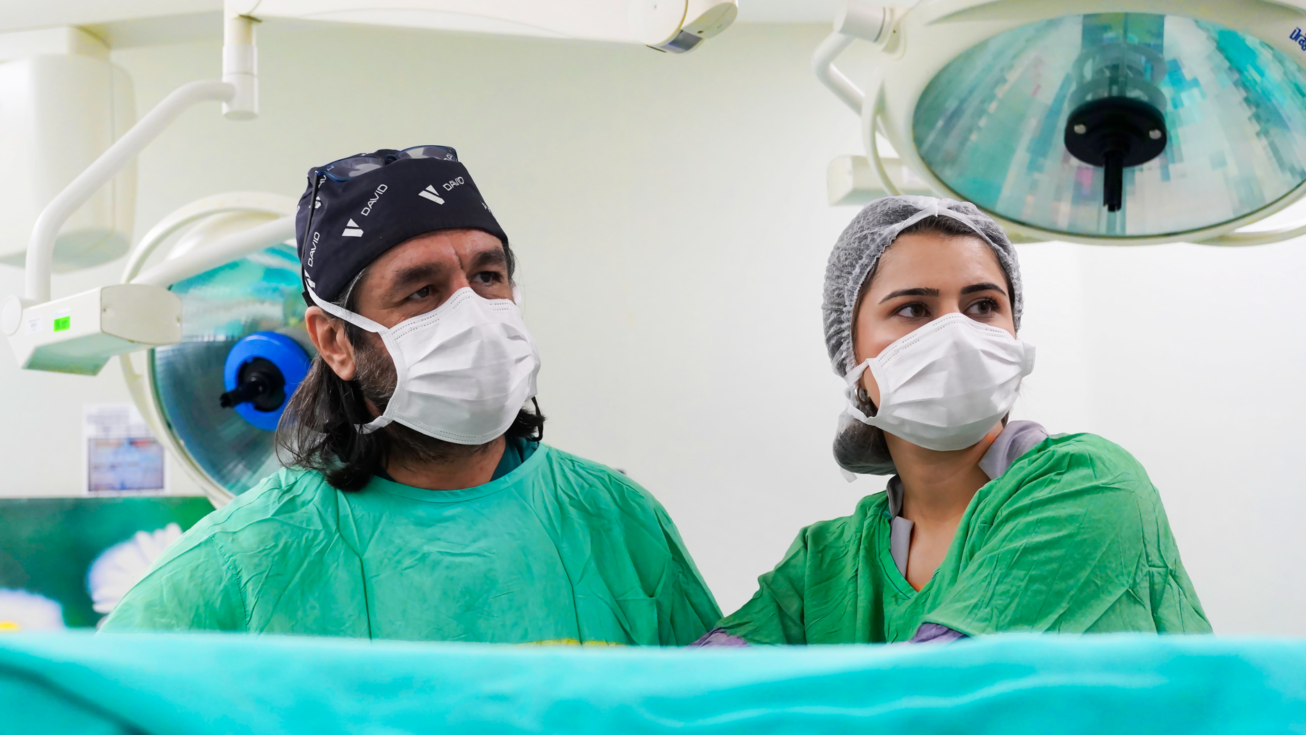 Two medical professionals focused during surgery in a sterile operating room environment.