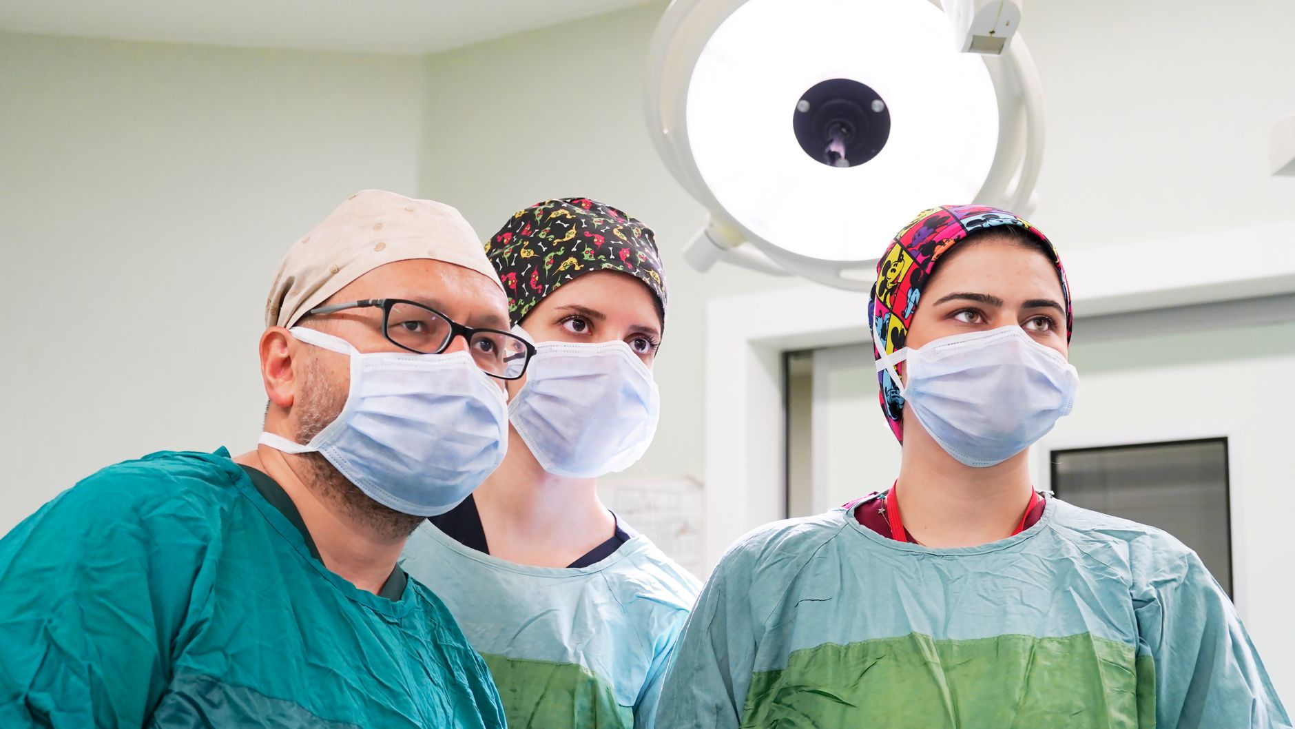 Team of surgeons focused during a procedure in a well-lit operating room.