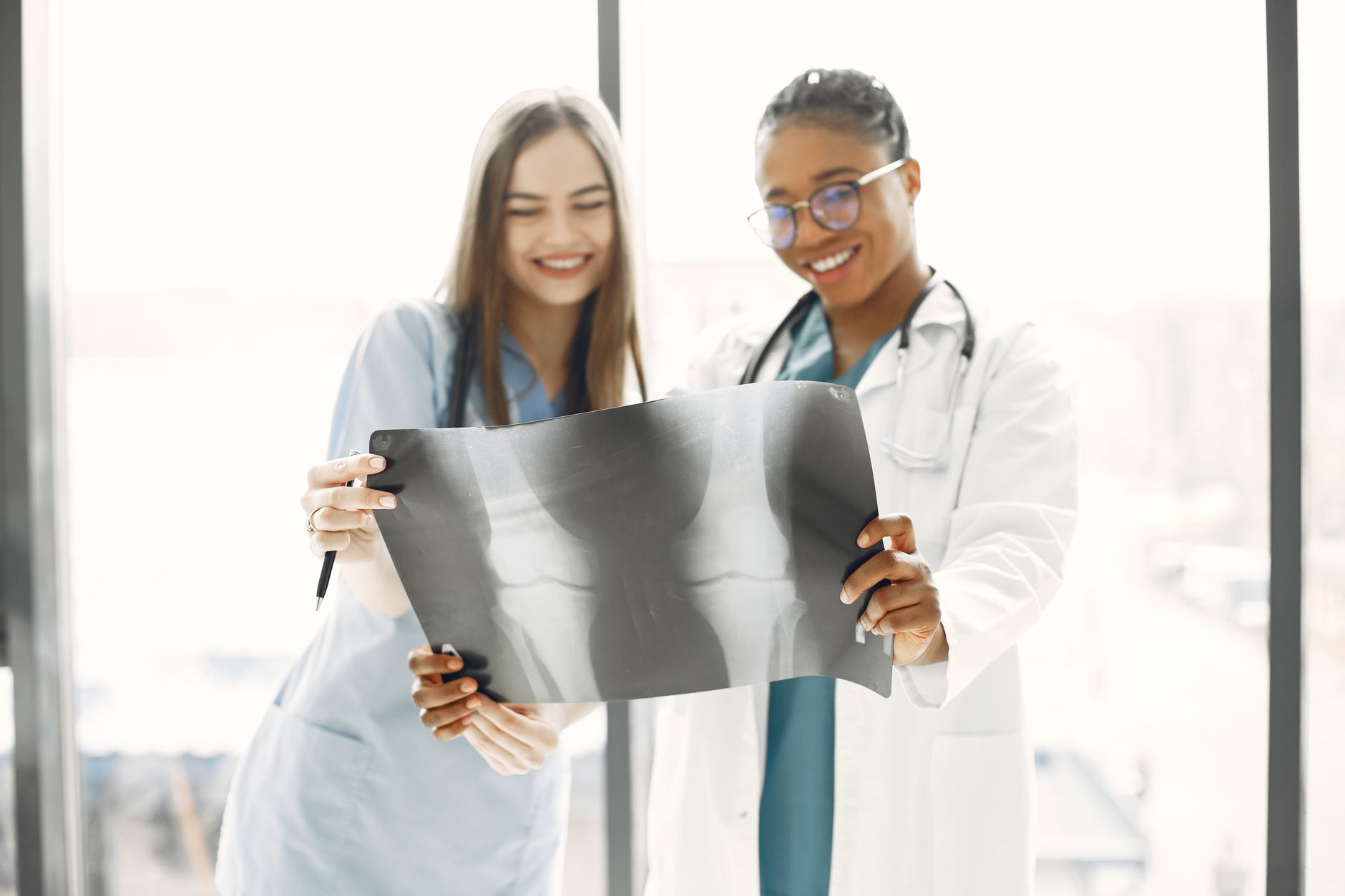 Two smiling healthcare professionals analyzing an X-ray in a brightly lit hospital room.