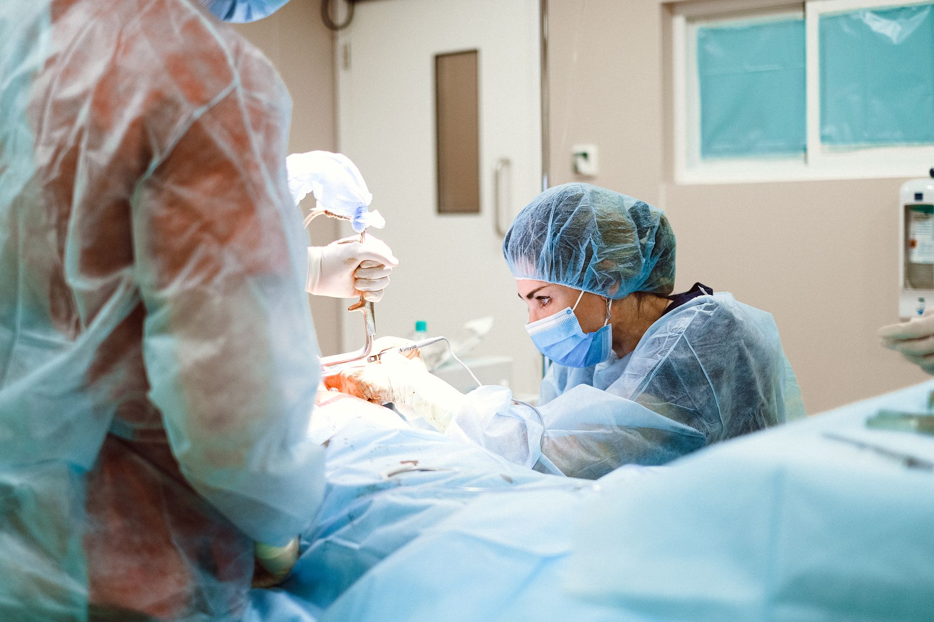 Female surgeon performing a surgical procedure in an operating room with sterile equipment.