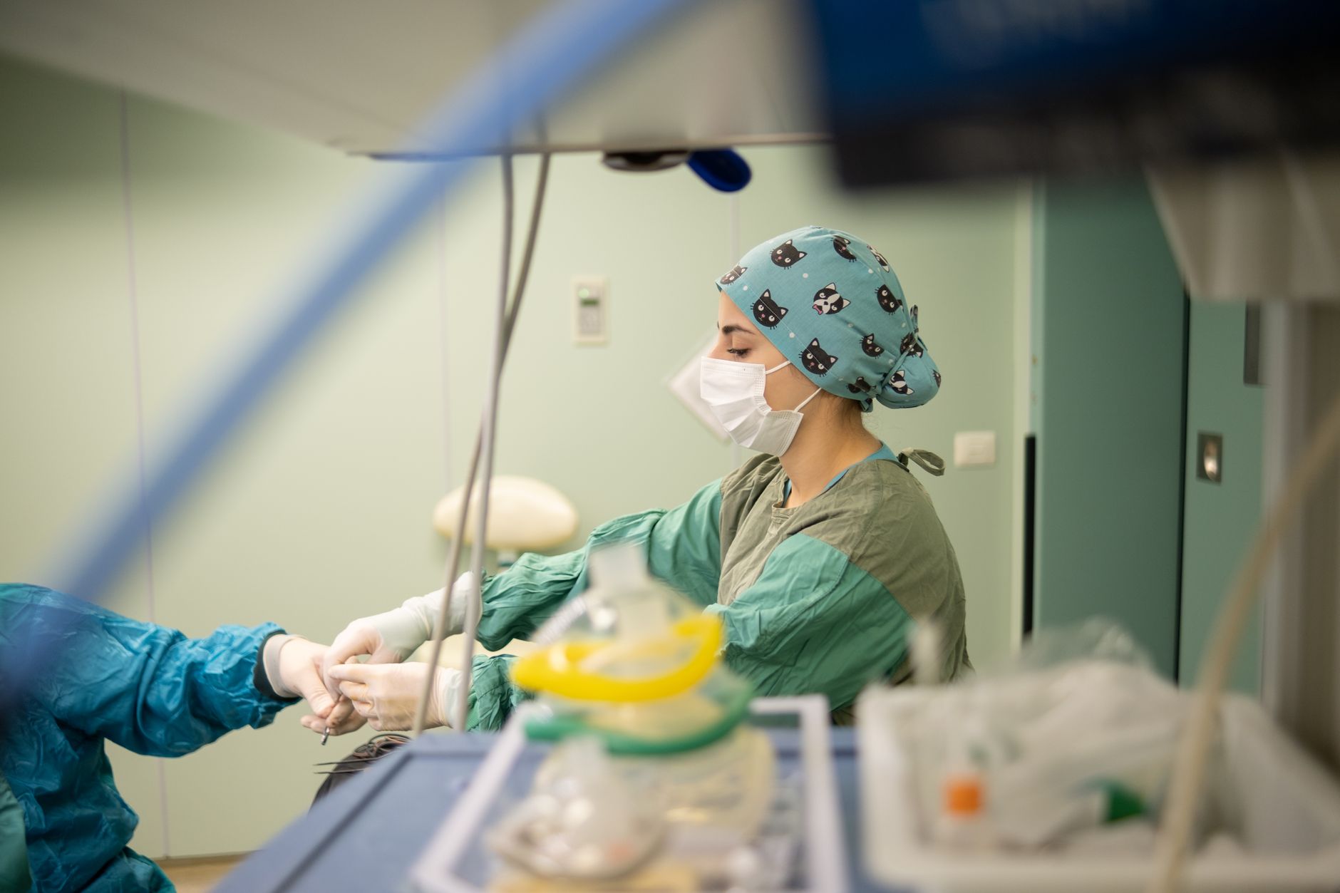 Focused nurse wearing a surgical mask assists during a procedure in a hospital operating room.