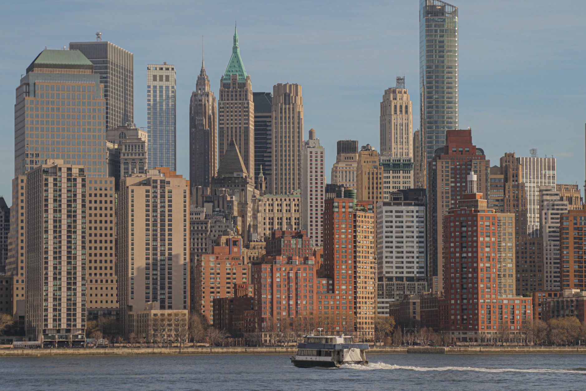Stunning view of New York City's iconic skyline featuring skyscrapers and a ferry on the Hudson River.