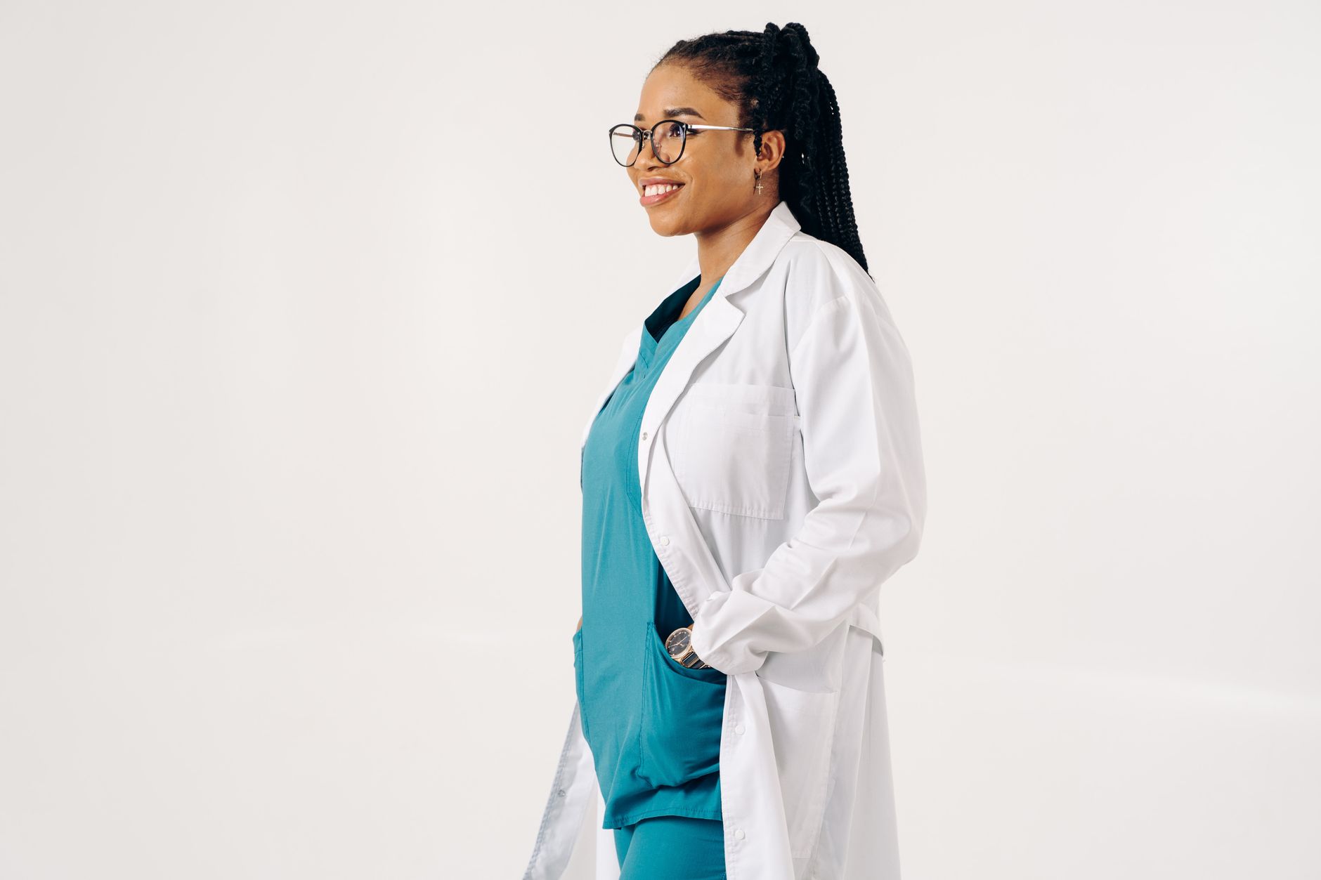 Smiling female doctor in uniform and eyeglasses standing against a white background.