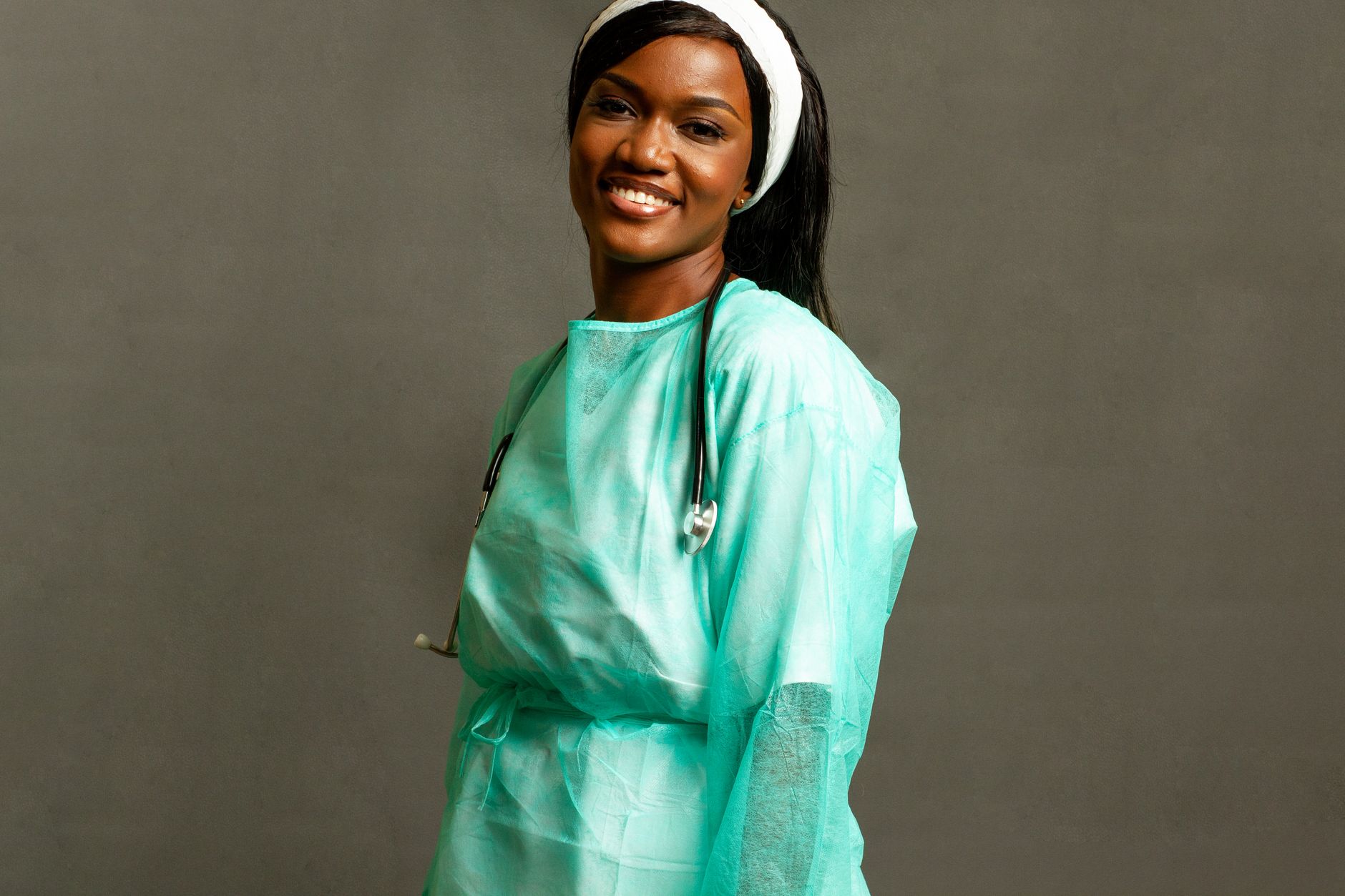 A cheerful female doctor in PPE with a stethoscope, posing in a studio setting.