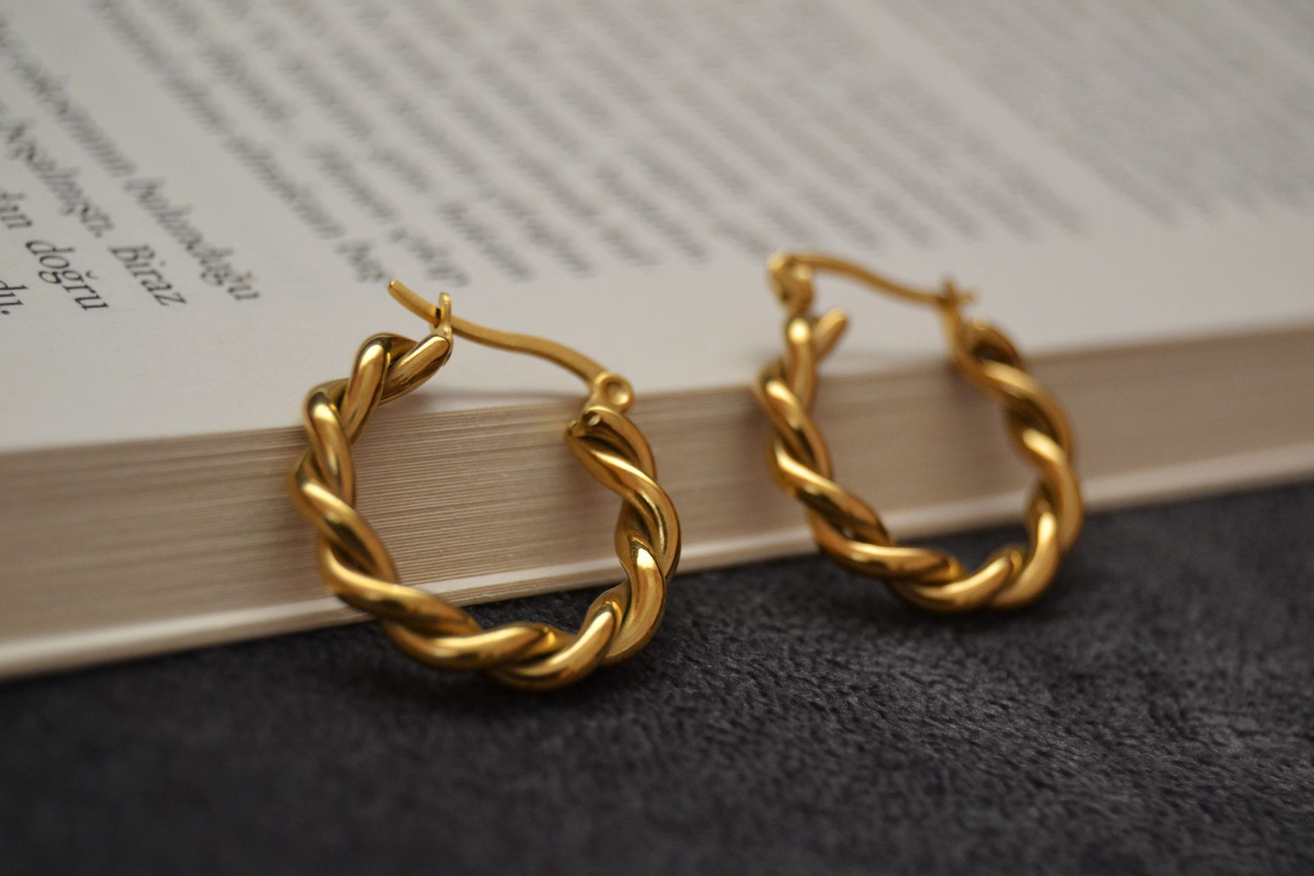 Elegant gold hoop earrings resting on an open book, perfect for fashion and style themes.