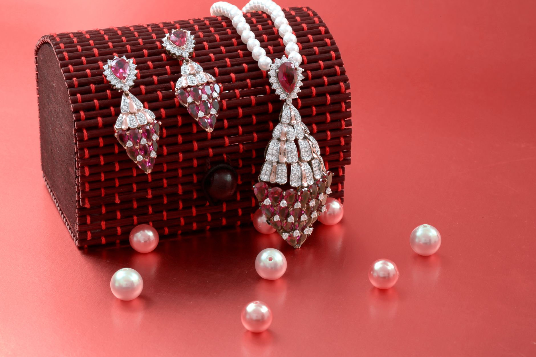 Exquisite ruby and pearl jewelry set with a necklace and earrings on a red background.