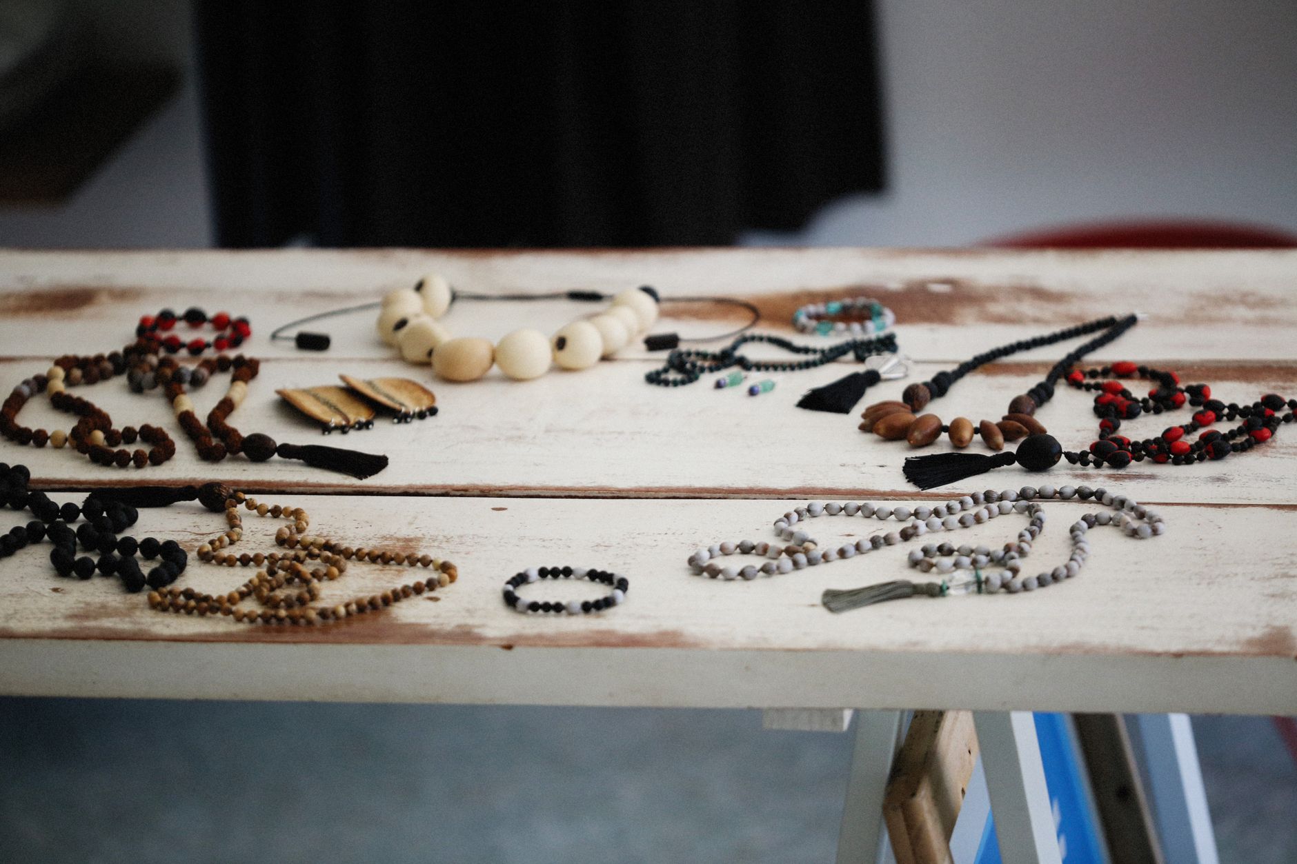 A collection of handmade bohemian necklaces and bracelets arranged on a rustic wooden table.