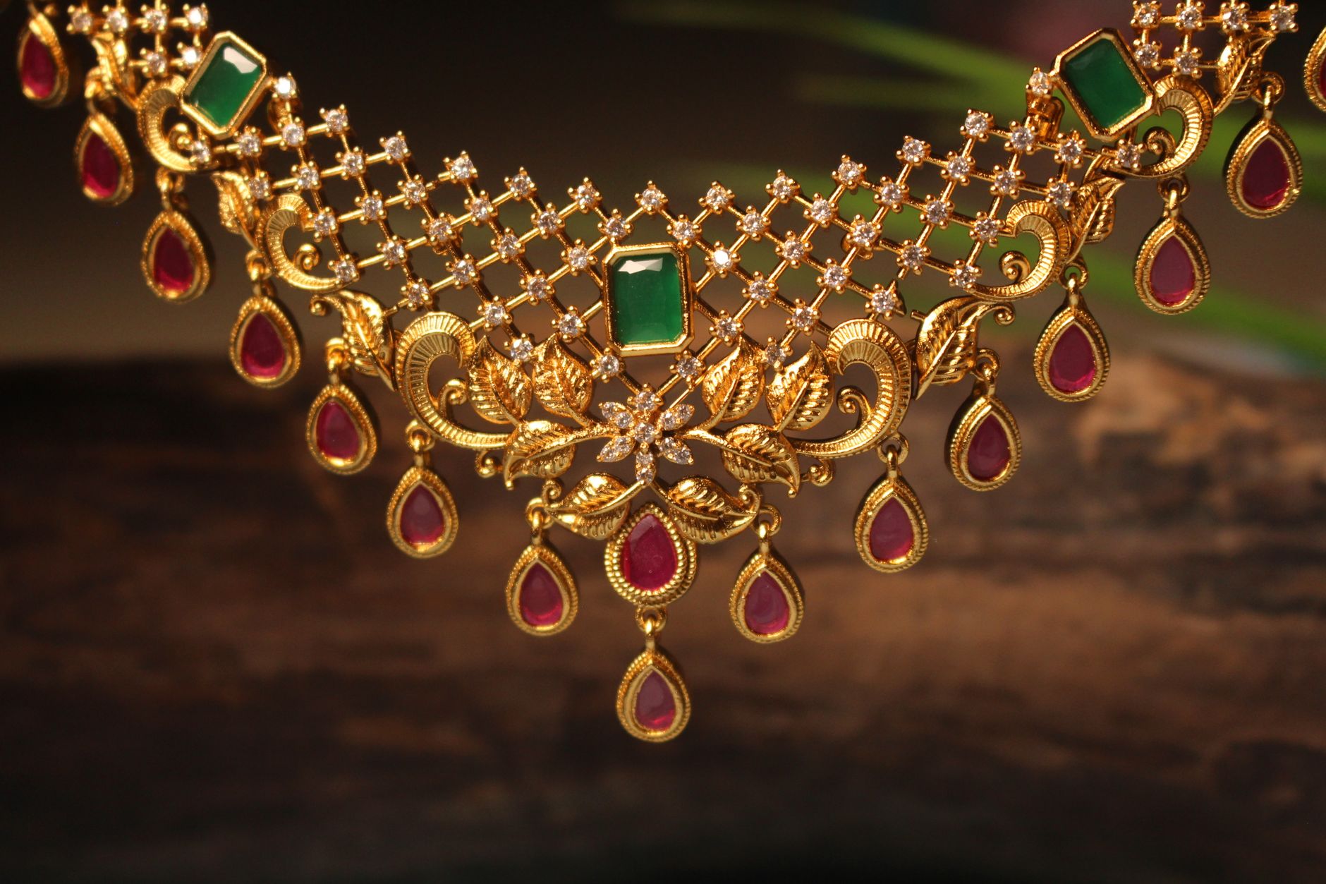 Luxurious gold necklace adorned with emerald and ruby gemstones, perfect for elegant occasions.