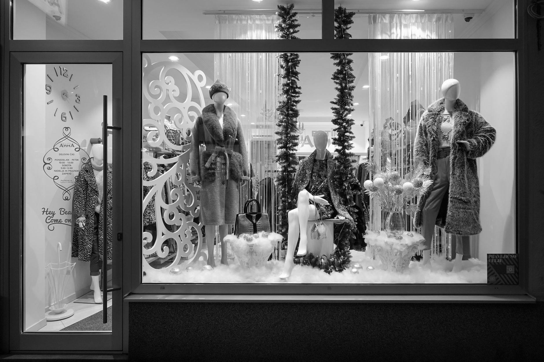 Black and white photo of a stylish store window with mannequins in winter attire.