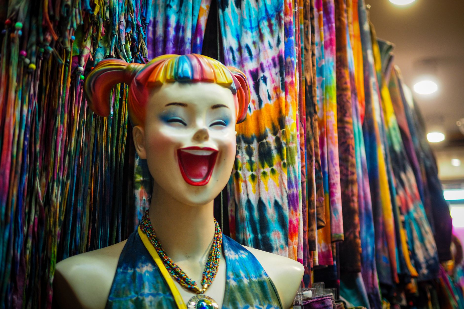 A striking mannequin with rainbow hair and vivid tie-dye fabrics in a lively store display.