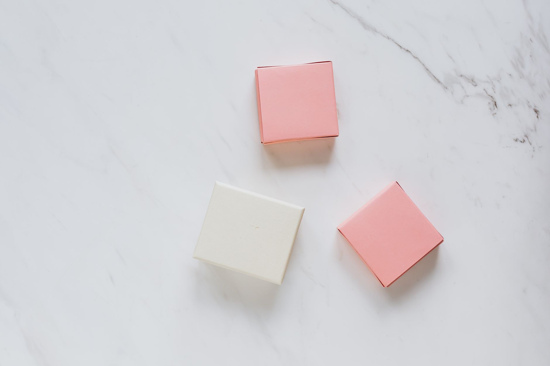 Top-down view of pastel pink and white gift boxes on a marble surface, perfect for branding or mockup purposes.