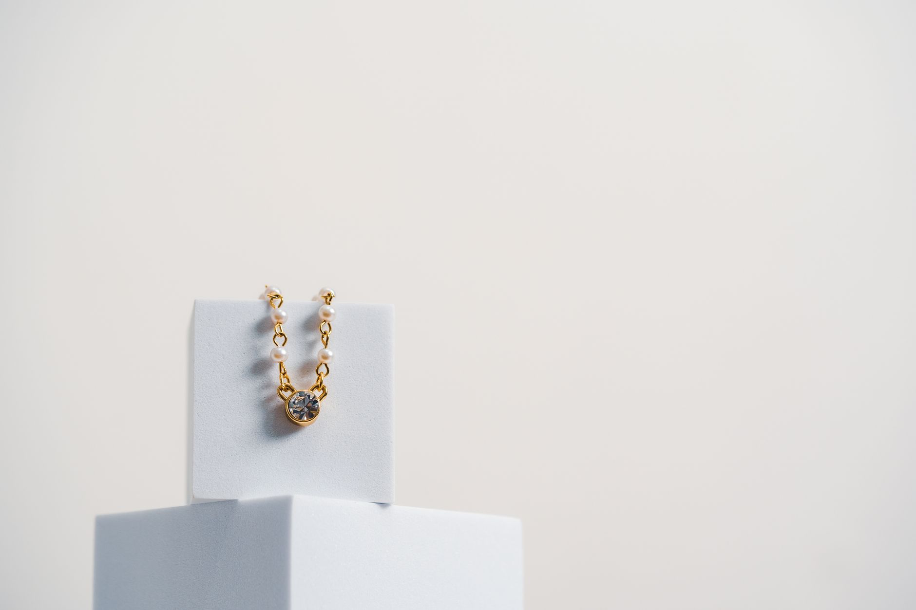 Gold necklace with diamond on minimalist display for luxury fashion.