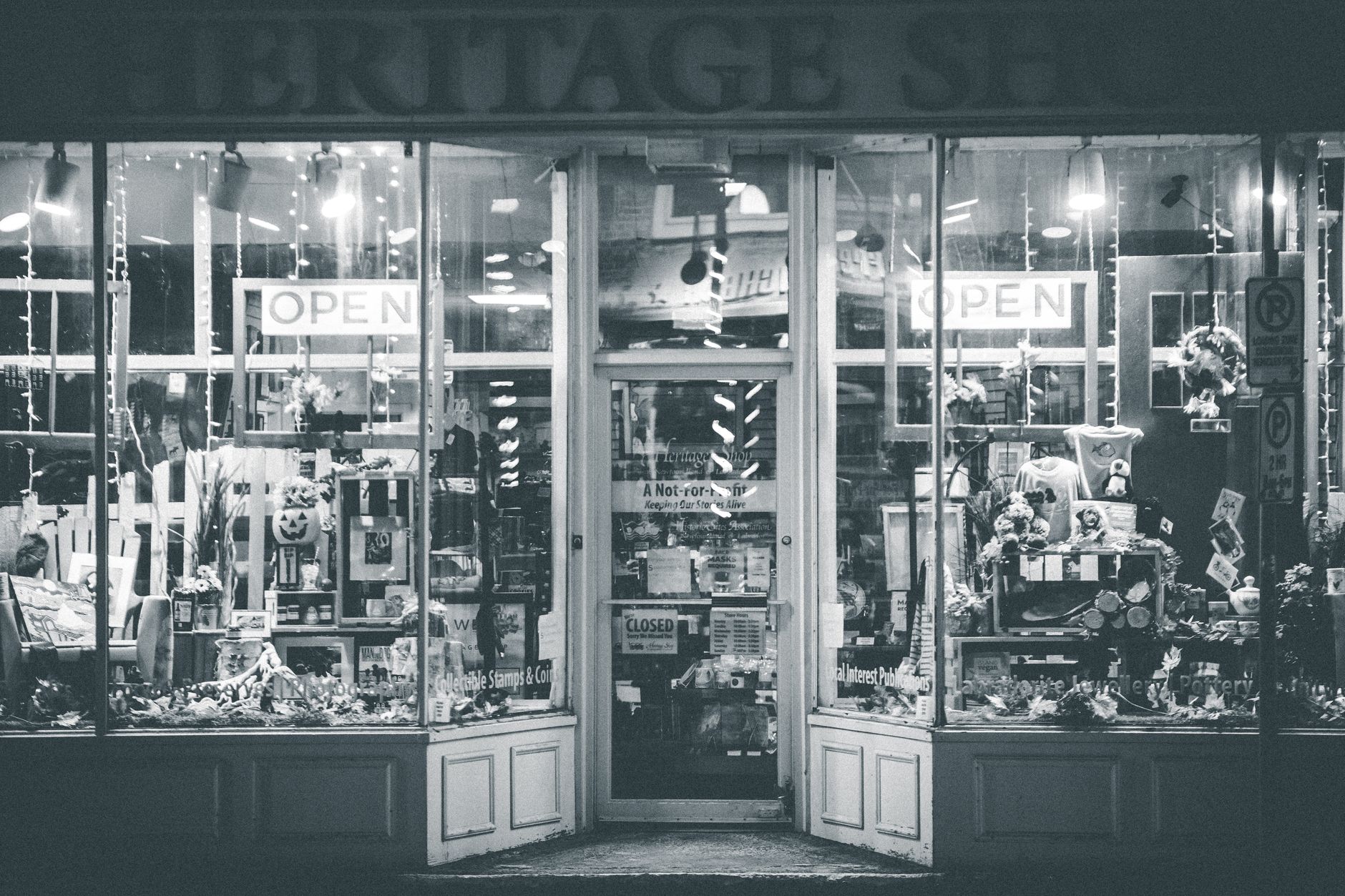 Black and white of store facade with entrance and souvenirs in glass window display located in street in city in evening time