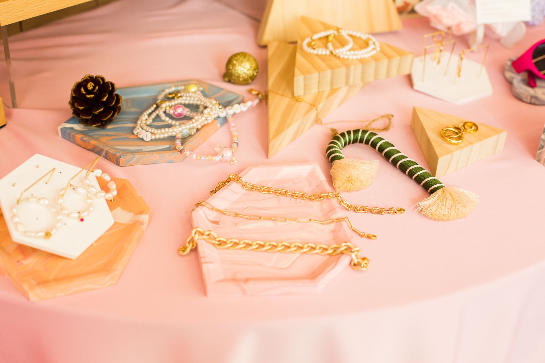 Chic collection of stylish jewelry displayed on a pink surface with geometric accents.