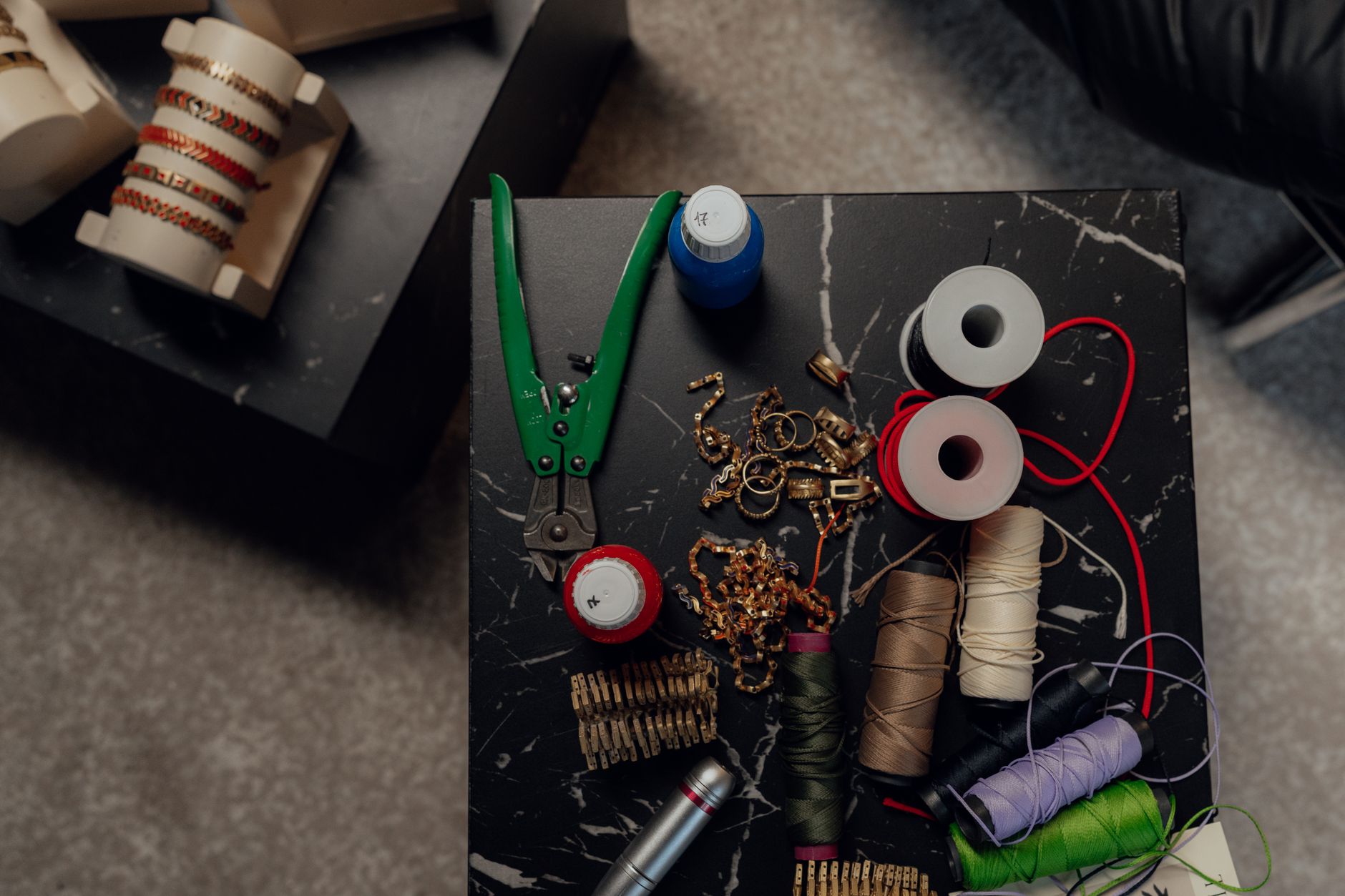 Top view of a crafting table with tools, spools, and jewelry making materials.