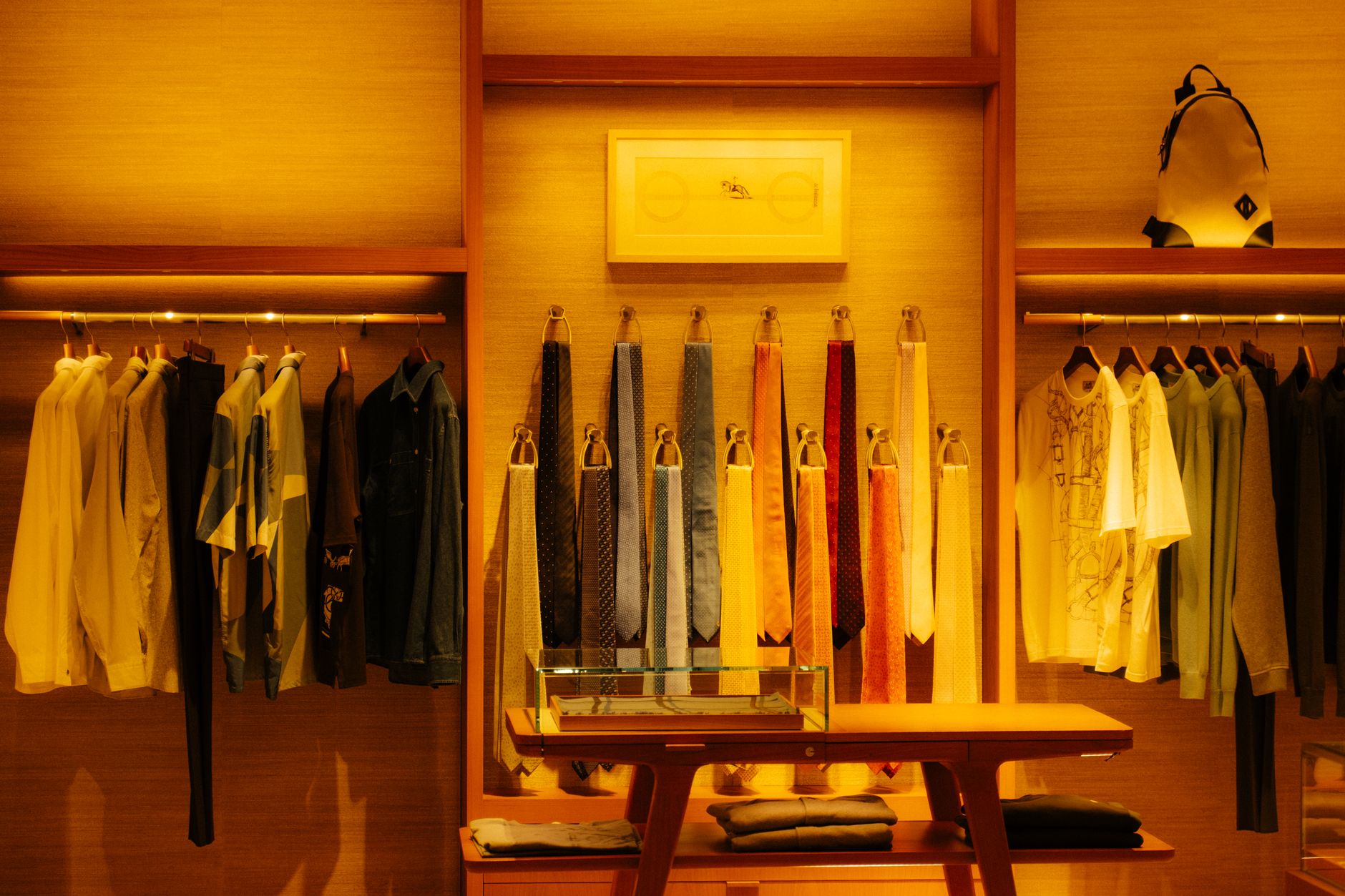Stylish fashion store interior showcasing clothes and accessories under warm lighting.