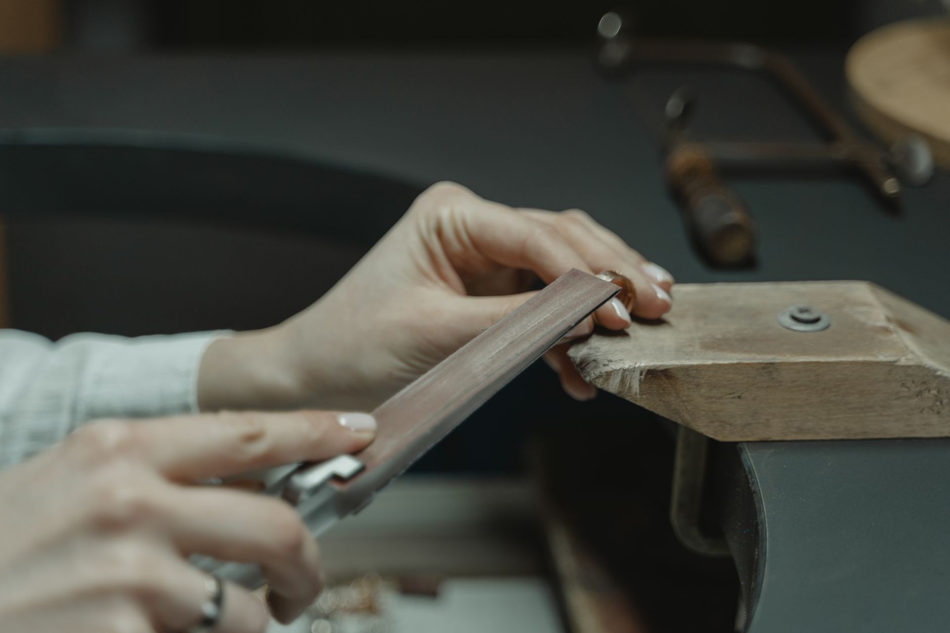 Artisan working meticulously on a jewelry piece at a wooden workbench.