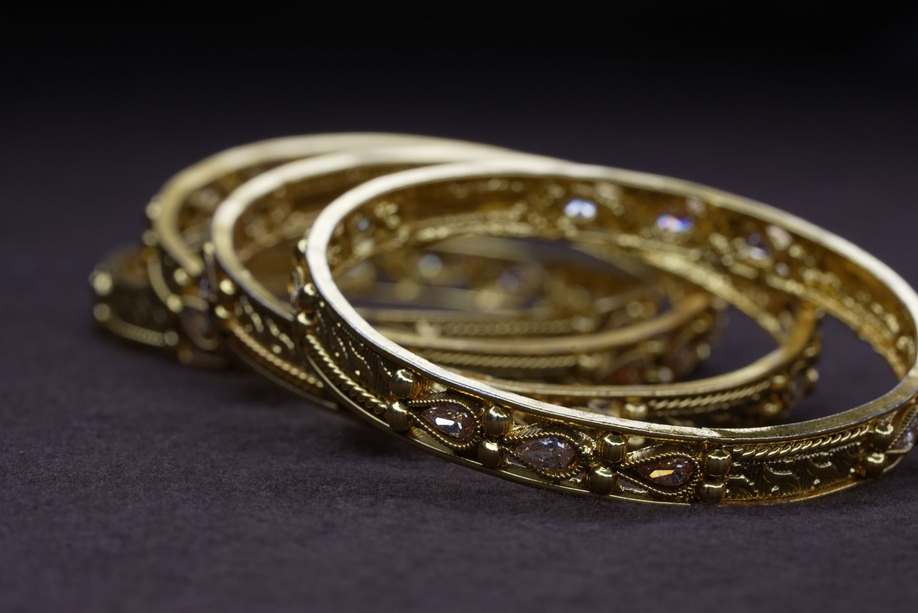 Detailed view of elegant golden bangles with intricate designs, perfect for jewelry enthusiasts.